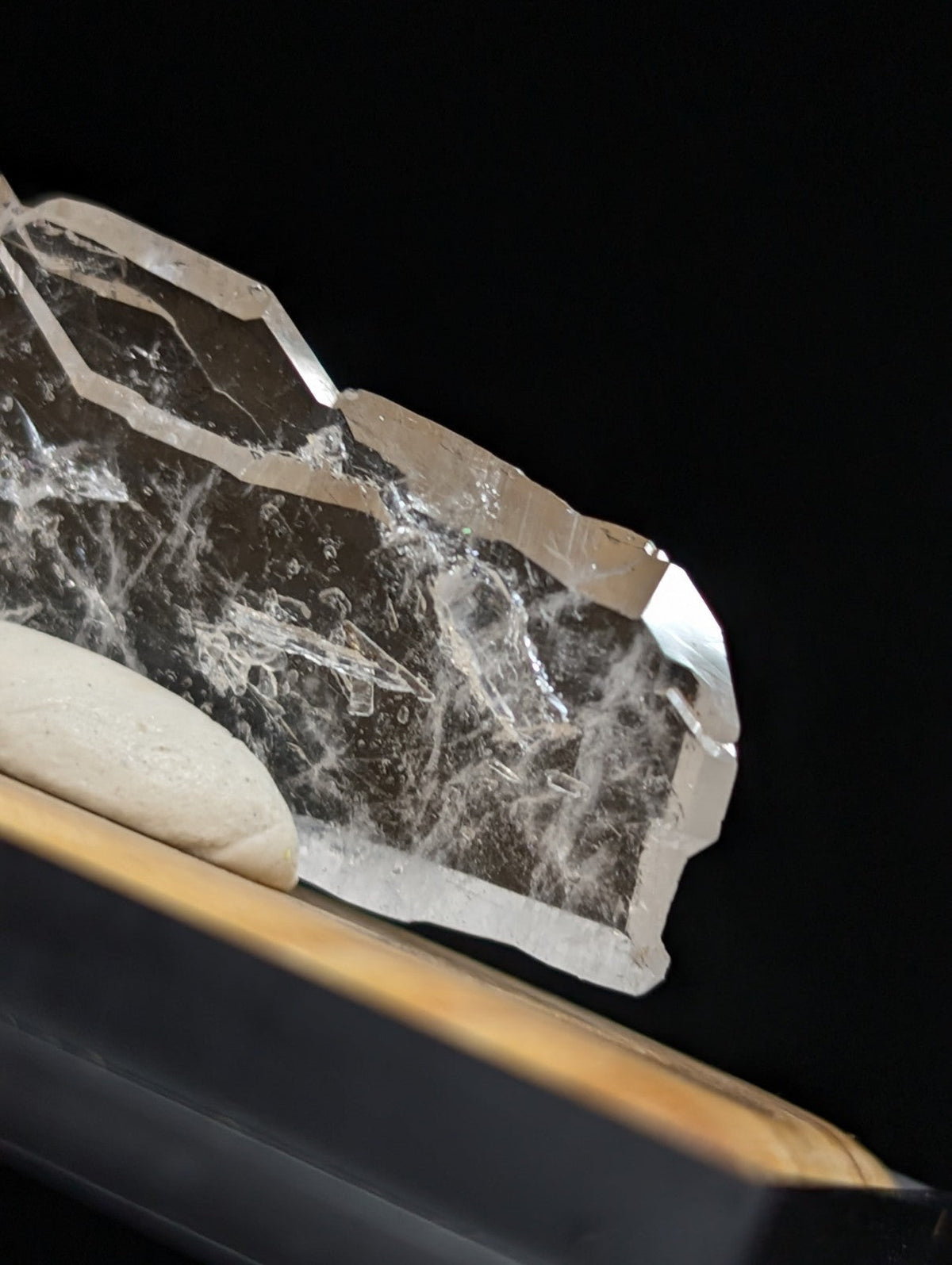 A translucent, clear quartz crystal with natural internal veining and a faceted edge.