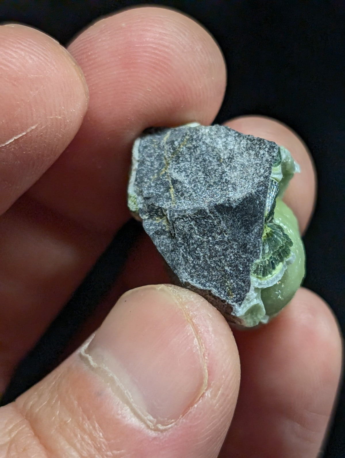 A rough, irregularly shaped green and gray mineral specimen with a partially polished surface.