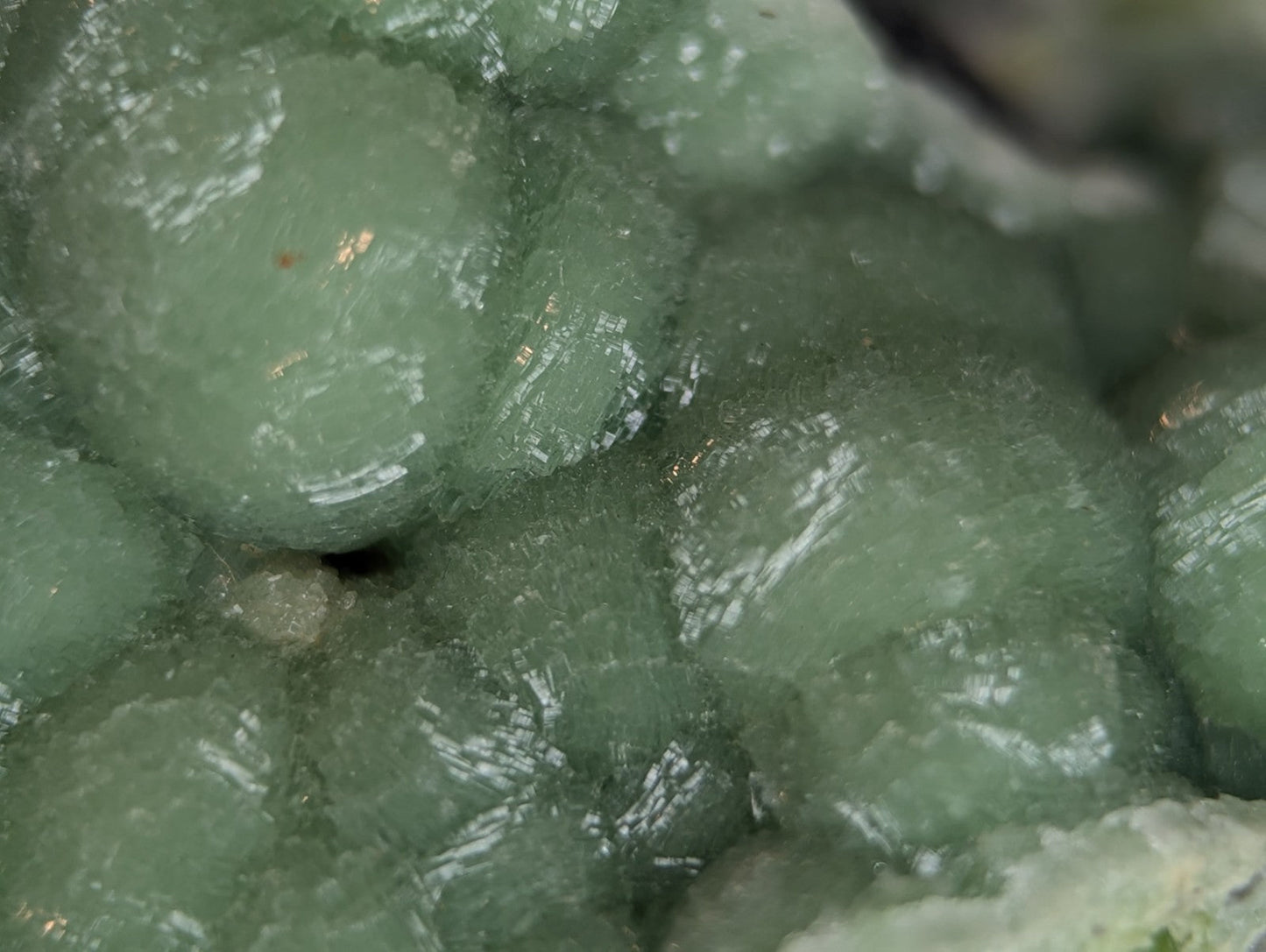 A cluster of translucent, pale green mineral crystals with a slightly rough and faceted surface.
