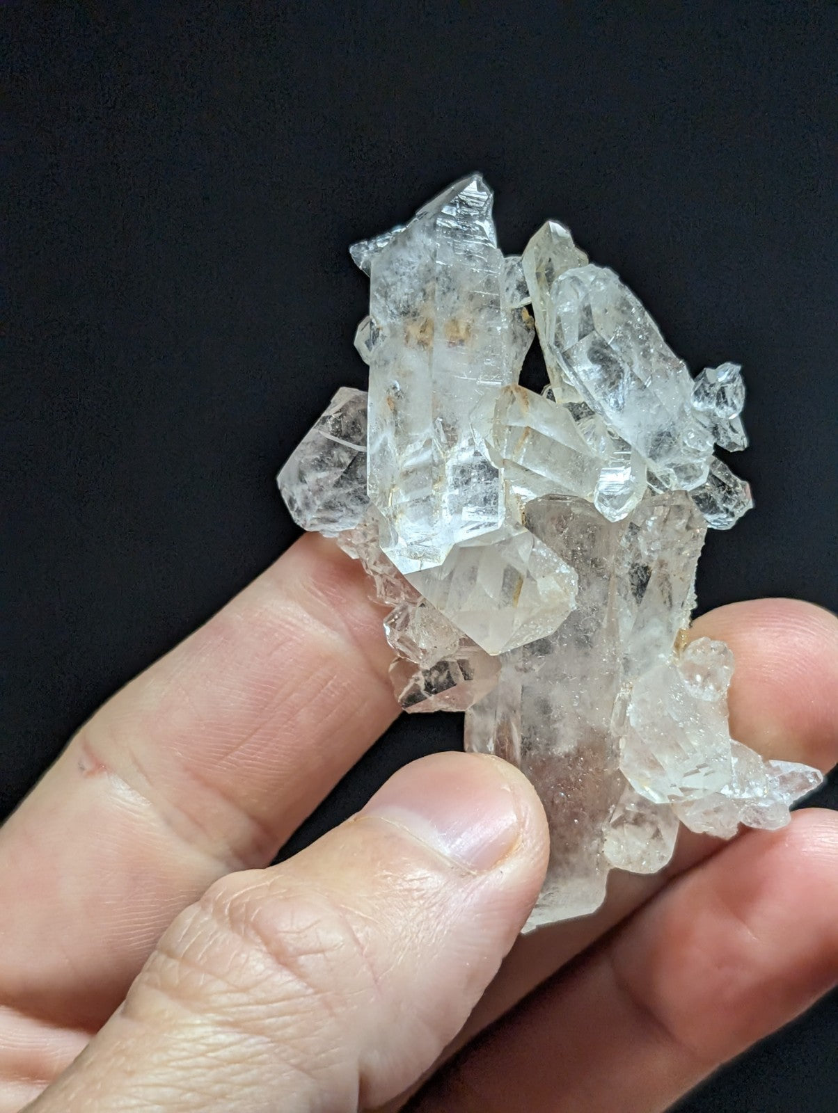 A cluster of clear, translucent quartz crystals with sharp, faceted edges and subtle internal inclusions.