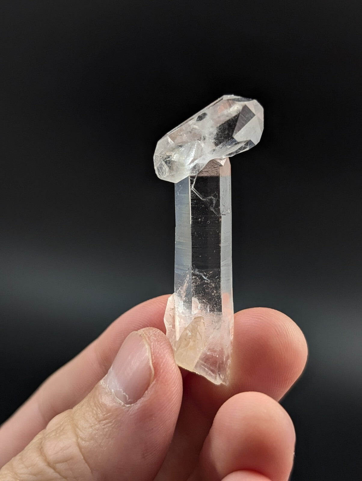 A clear, translucent quartz crystal with a pointed top and faceted edges.