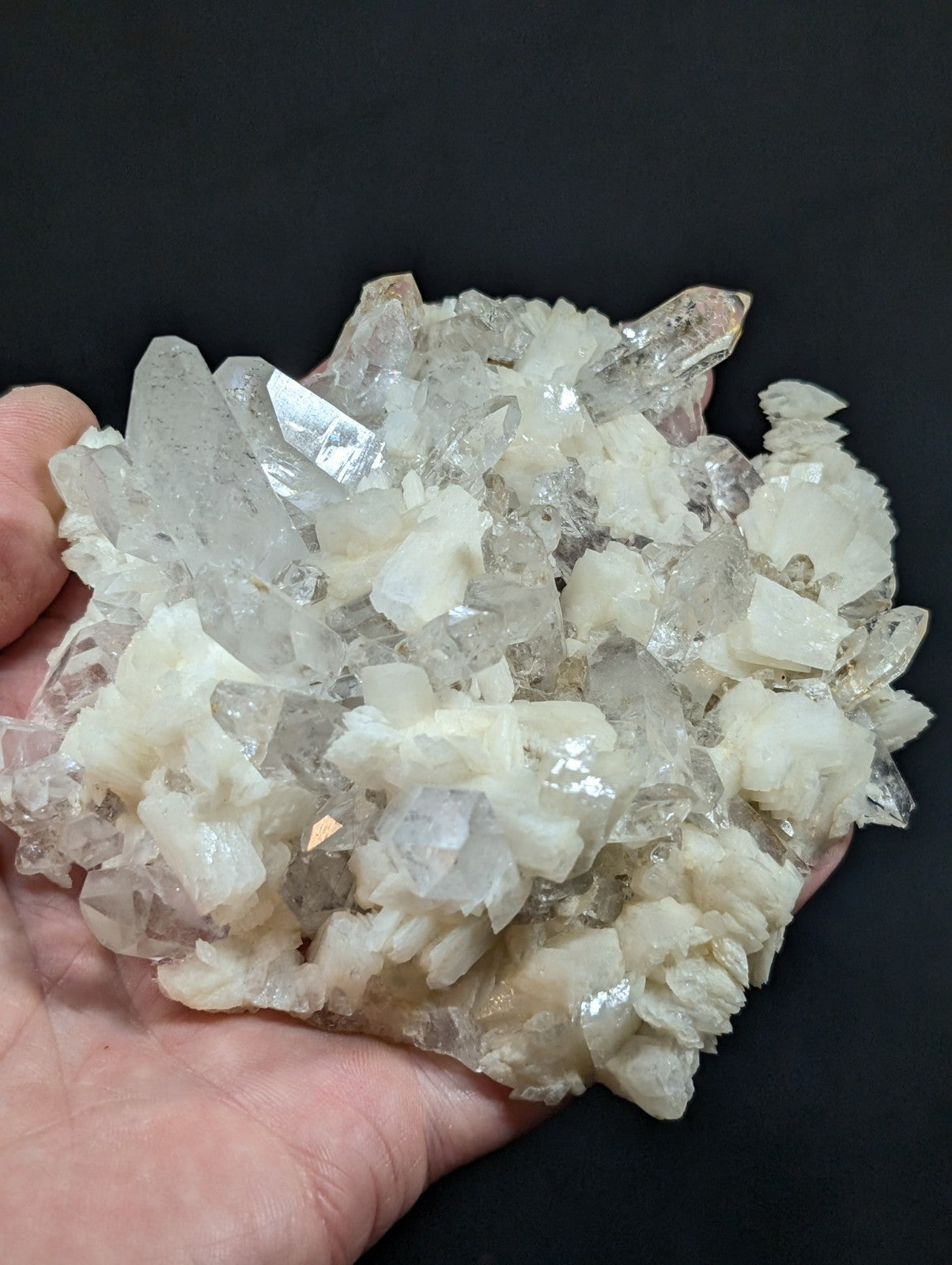 A cluster of translucent, clear quartz crystals with some exhibiting a milky white hue and sharp, pointed facets.