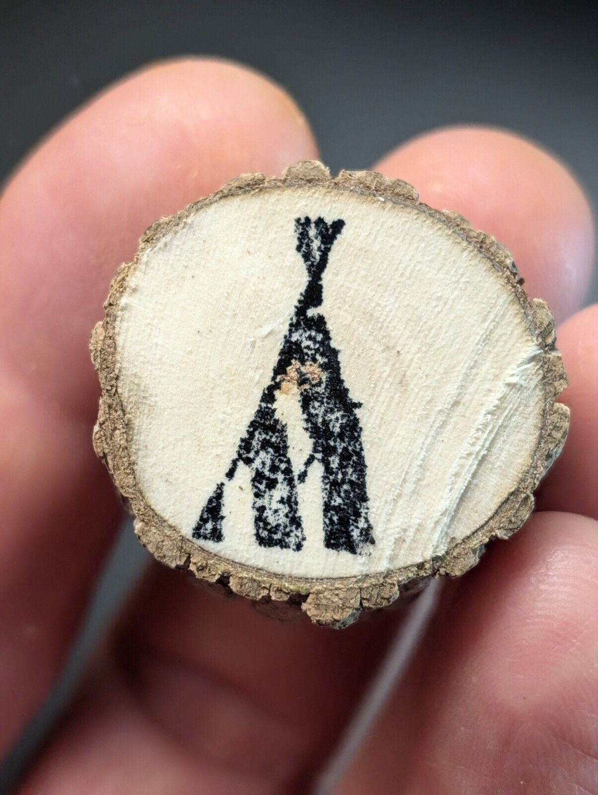 Wood slice with teepee drawing.