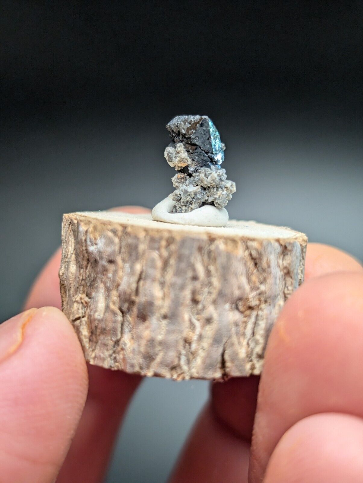 Iridescent mineral specimen on wood base.