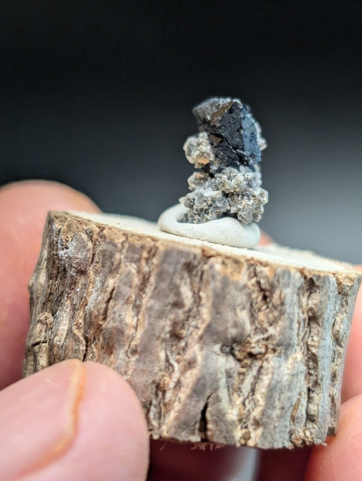 Miniature mineral specimen on wood base.