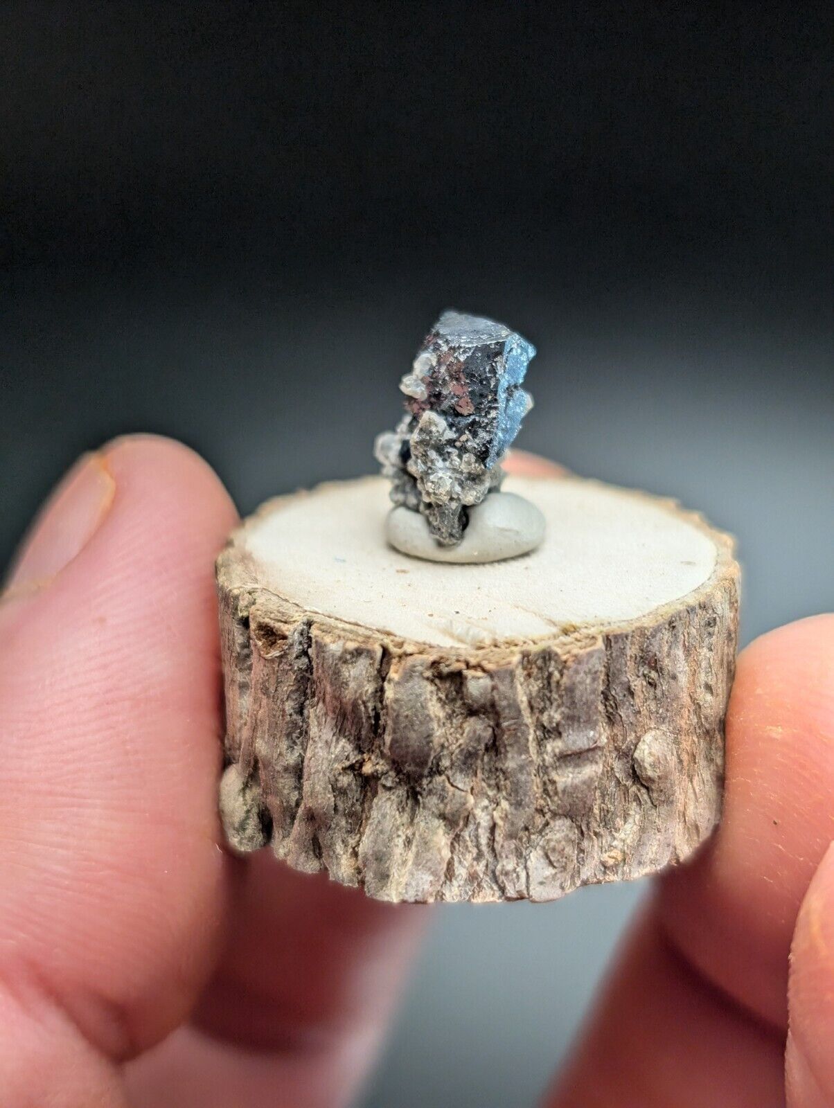 Metallic crystal specimen on a wooden base.