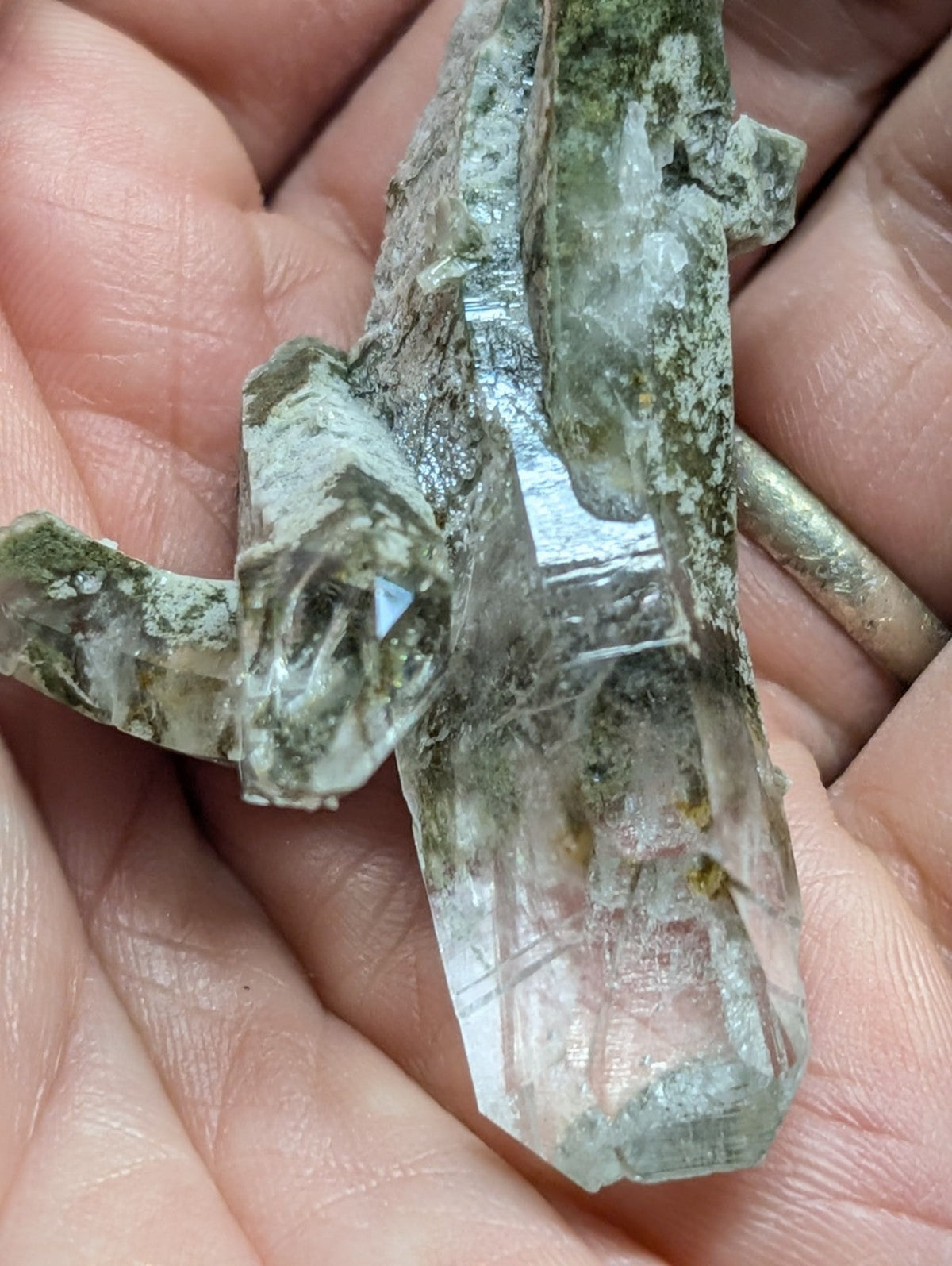 A translucent greenish quartz crystal cluster with visible internal striations and a rough, earthy matrix.