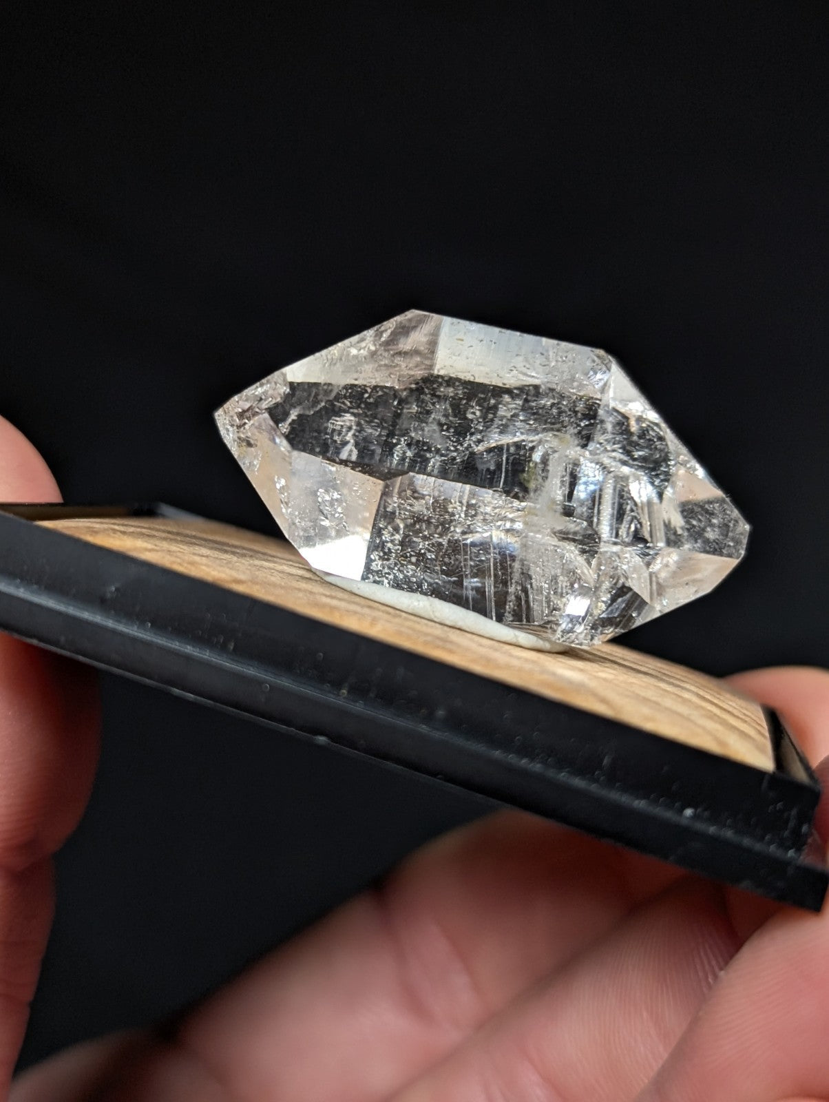 A clear, faceted quartz crystal with natural inclusions and a polished geometric cut.