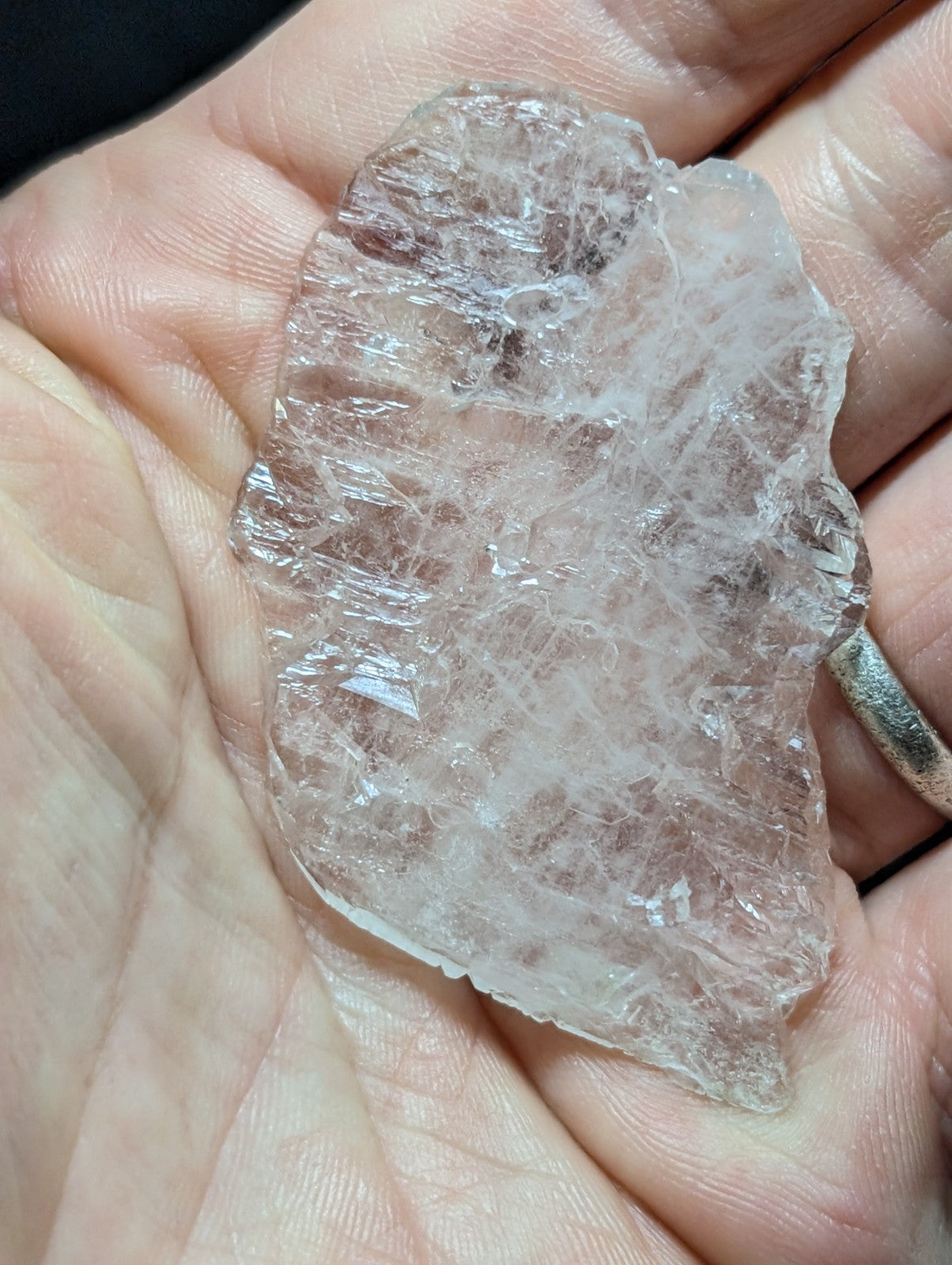 A translucent, clear quartz crystal with a rough, natural edge and visible internal striations.