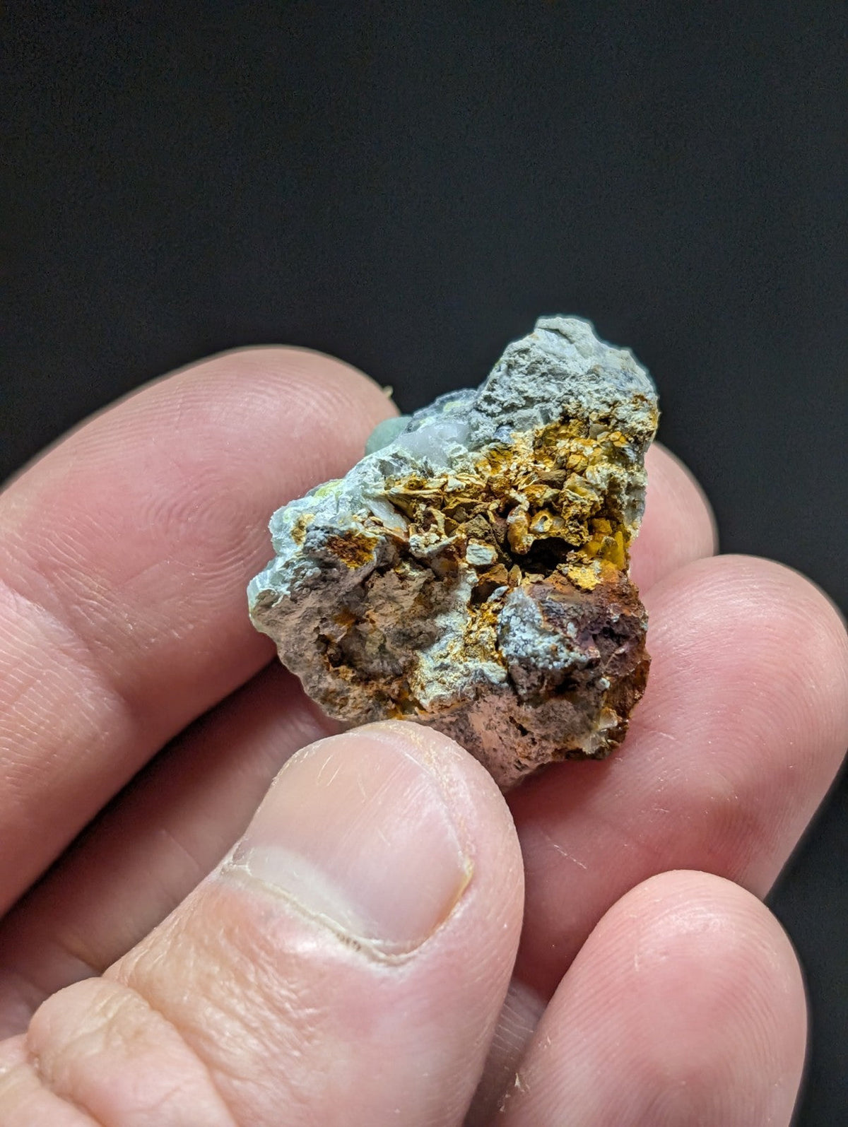 A rugged, irregularly shaped mineral specimen with a mix of grayish-blue and golden-yellow hues.
