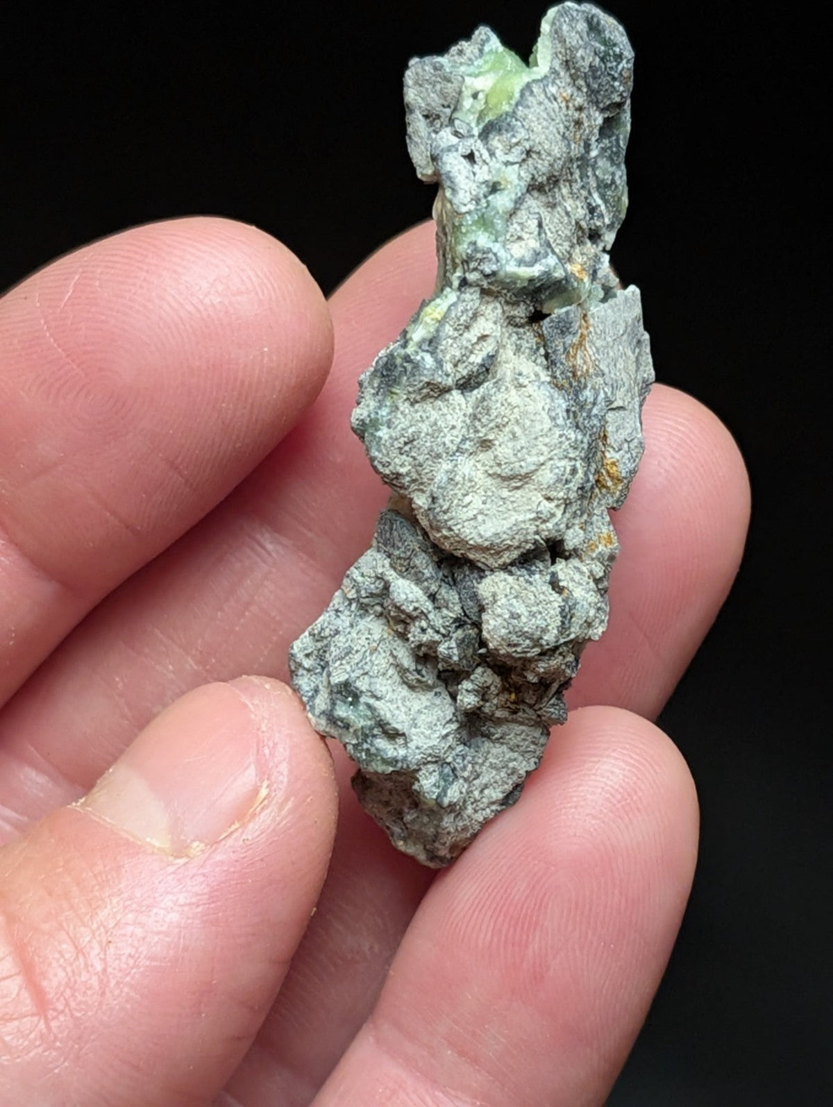A weathered, irregularly shaped mineral specimen with a mottled green and gray patina.