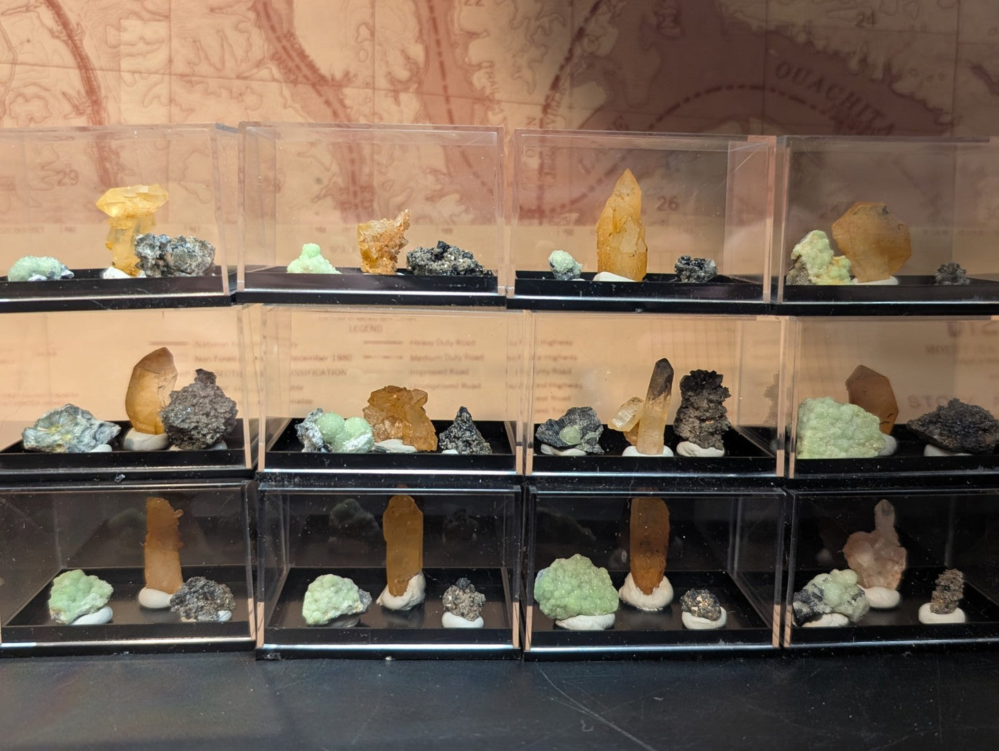 Clear acrylic display cases each holding a variety of colorful mineral specimens.