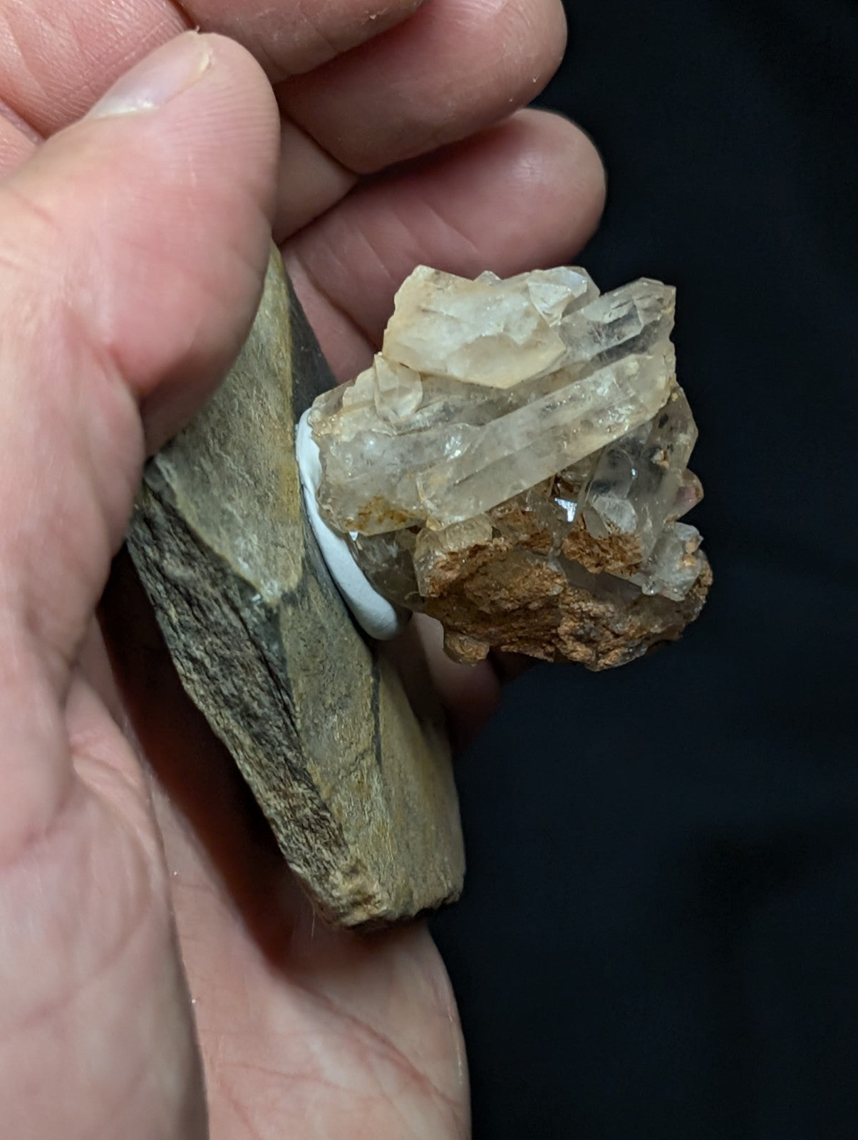 A cluster of translucent, pale yellowish quartz crystals with sharp facets and a rough, earthy matrix base.