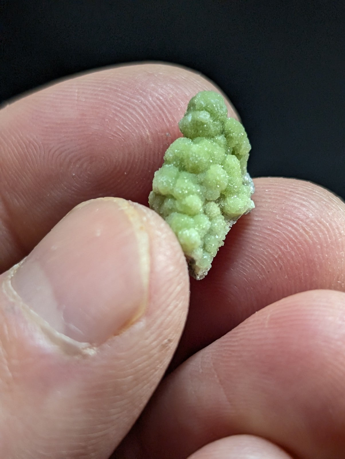 A small, textured green mineral specimen with a crystalline, bumpy surface.