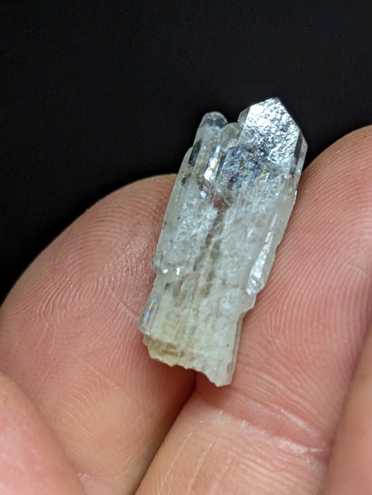 A translucent, pale greenish-white quartz crystal cluster with a faceted, pointed top and rougher base.