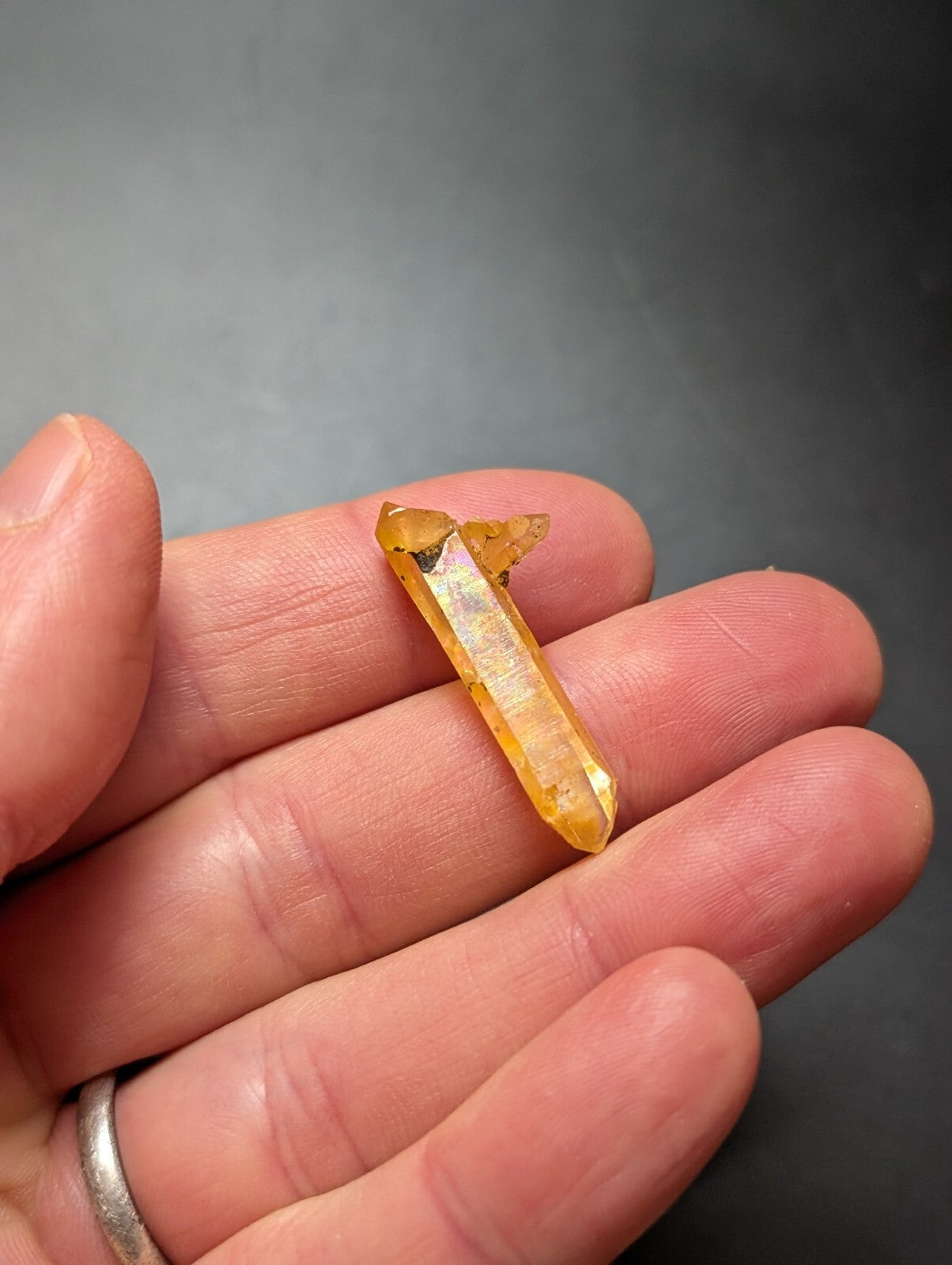 A translucent golden-yellow citrine crystal with a pointed, faceted tip and natural imperfections.