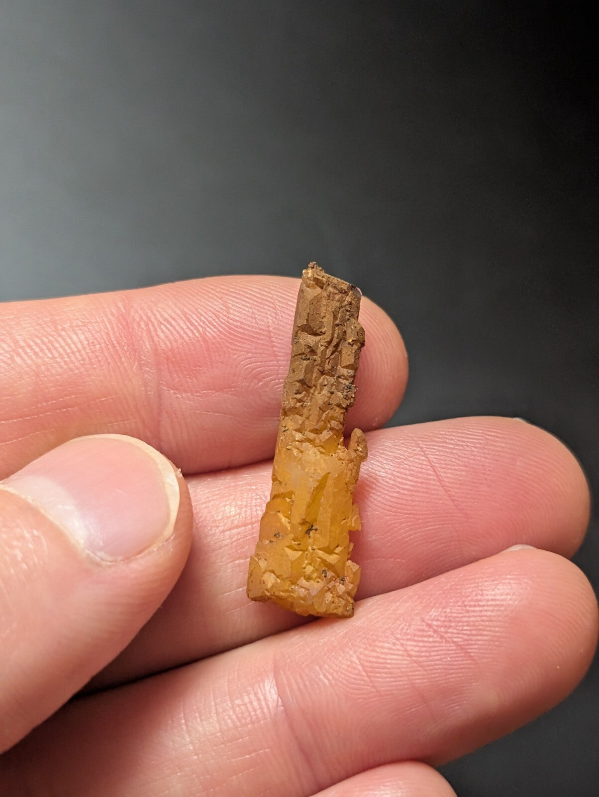 A weathered, amber-hued fragment of ancient stone with a rough, textured surface and visible chipped edges.