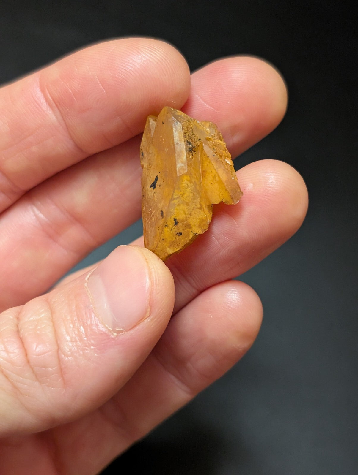 A translucent amber-colored mineral crystal with visible internal inclusions and a rough, jagged surface.