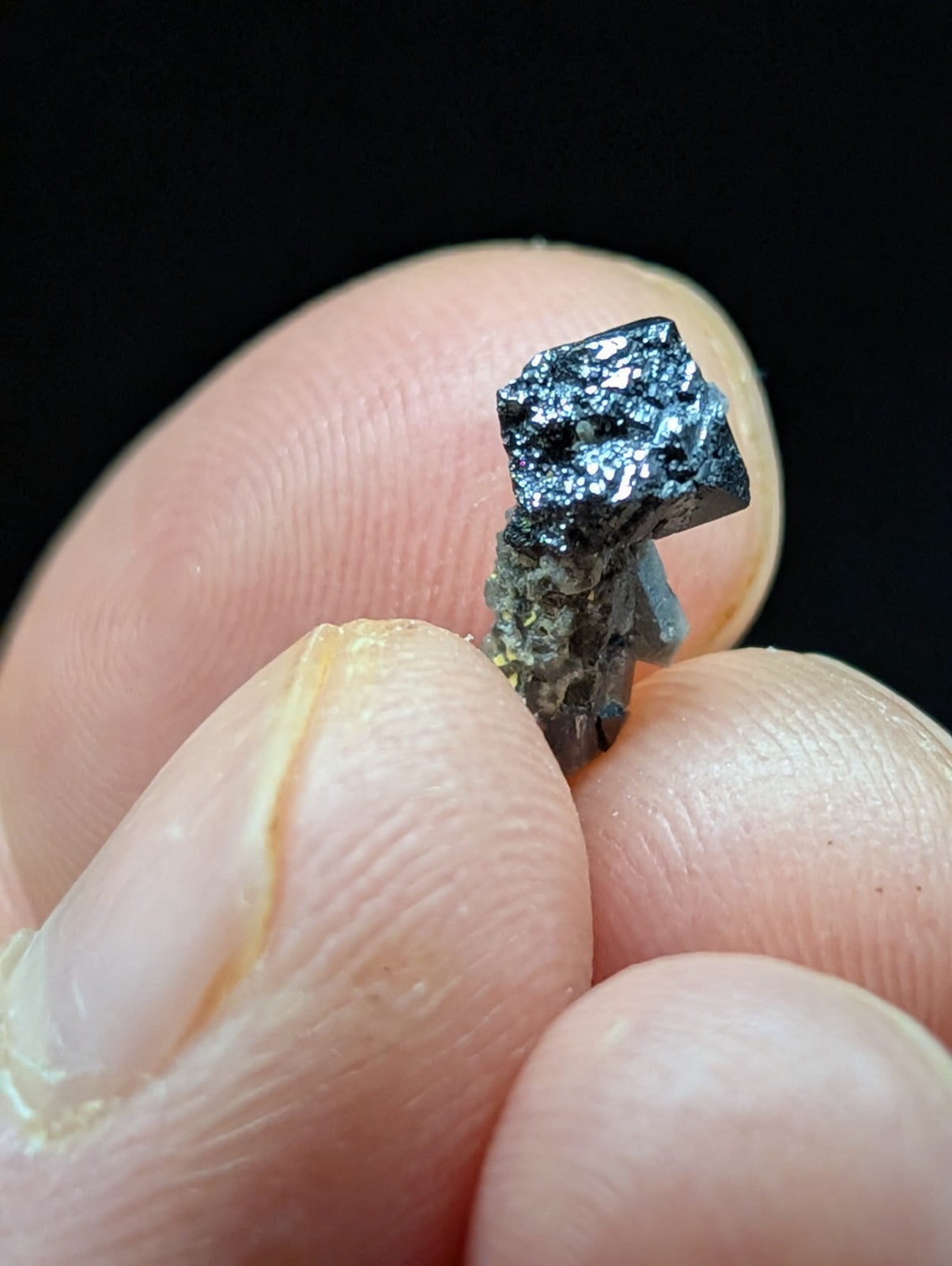 A dark, metallic mineral specimen with a crystalline structure and speckled surface.