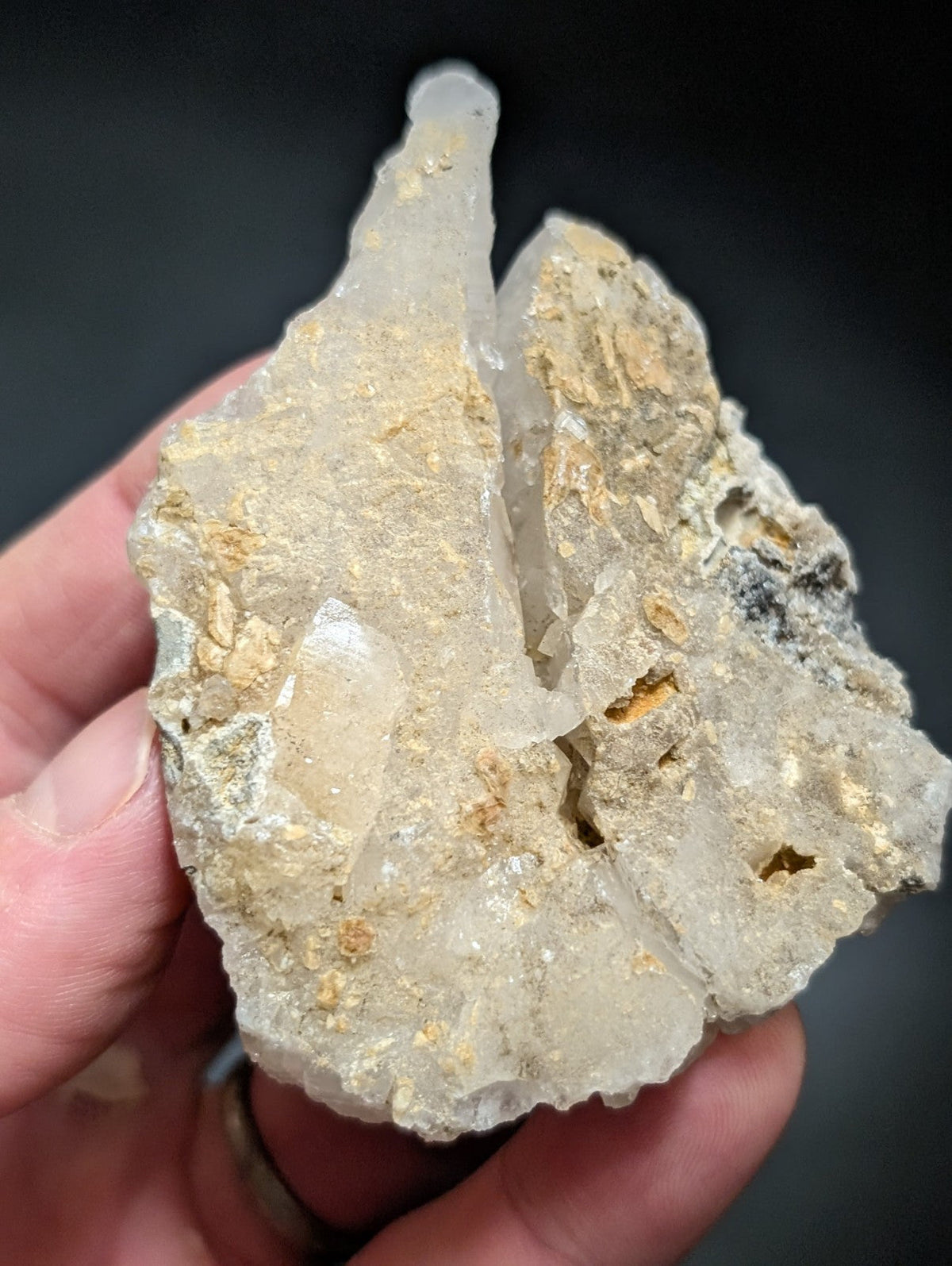 A translucent, pale quartz crystal cluster with golden mineral inclusions and rough, jagged edges.