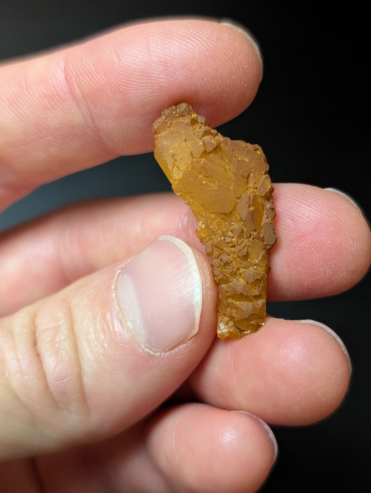 A translucent amber-colored mineral fragment with a rough, irregular surface and visible internal crystalline structure.