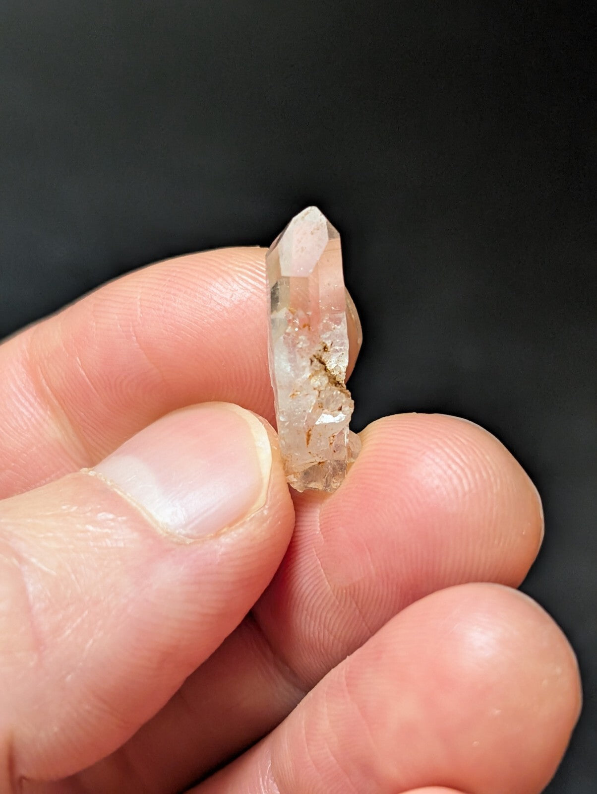 A translucent, pale quartz crystal with a pointed tip and visible internal inclusions.