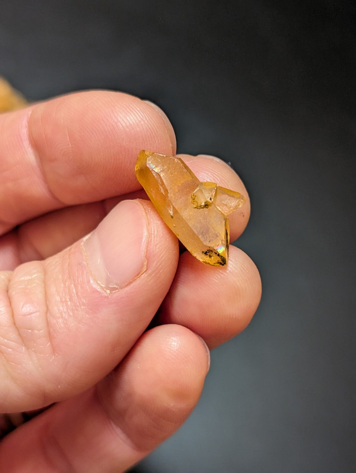 A translucent amber-colored crystal with a faceted, pointed shape and subtle golden inclusions.