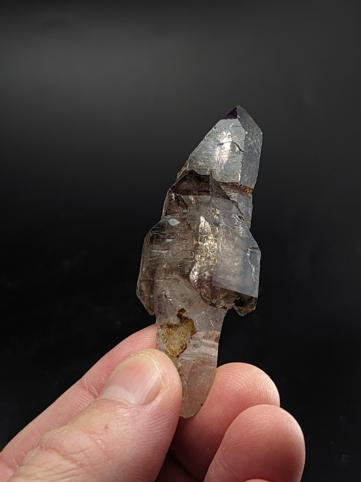 A translucent smoky quartz crystal point with natural inclusions and a pointed, faceted tip.