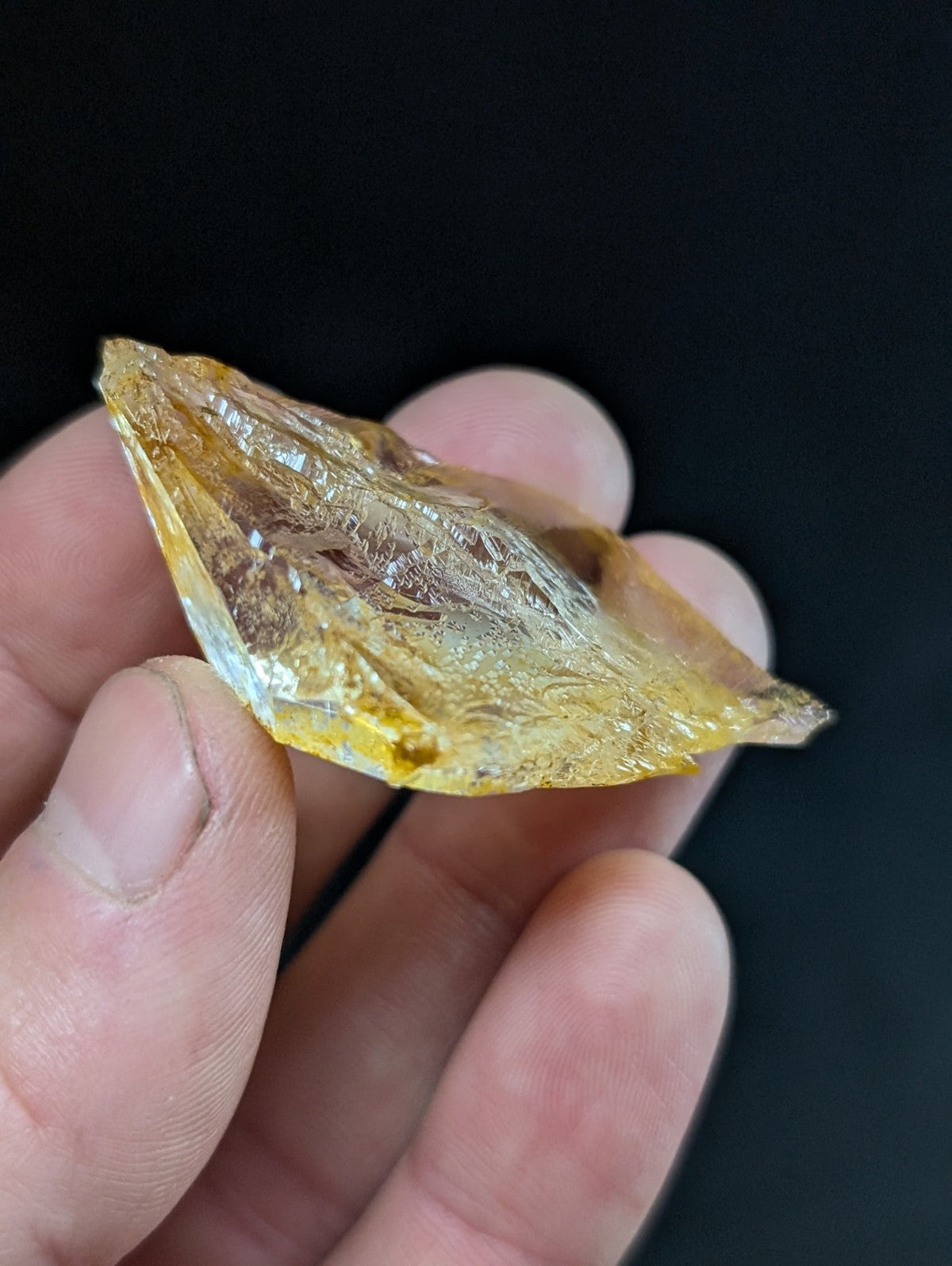 A translucent amber-colored resin fragment with a glossy, irregularly shaped surface and visible internal inclusions.