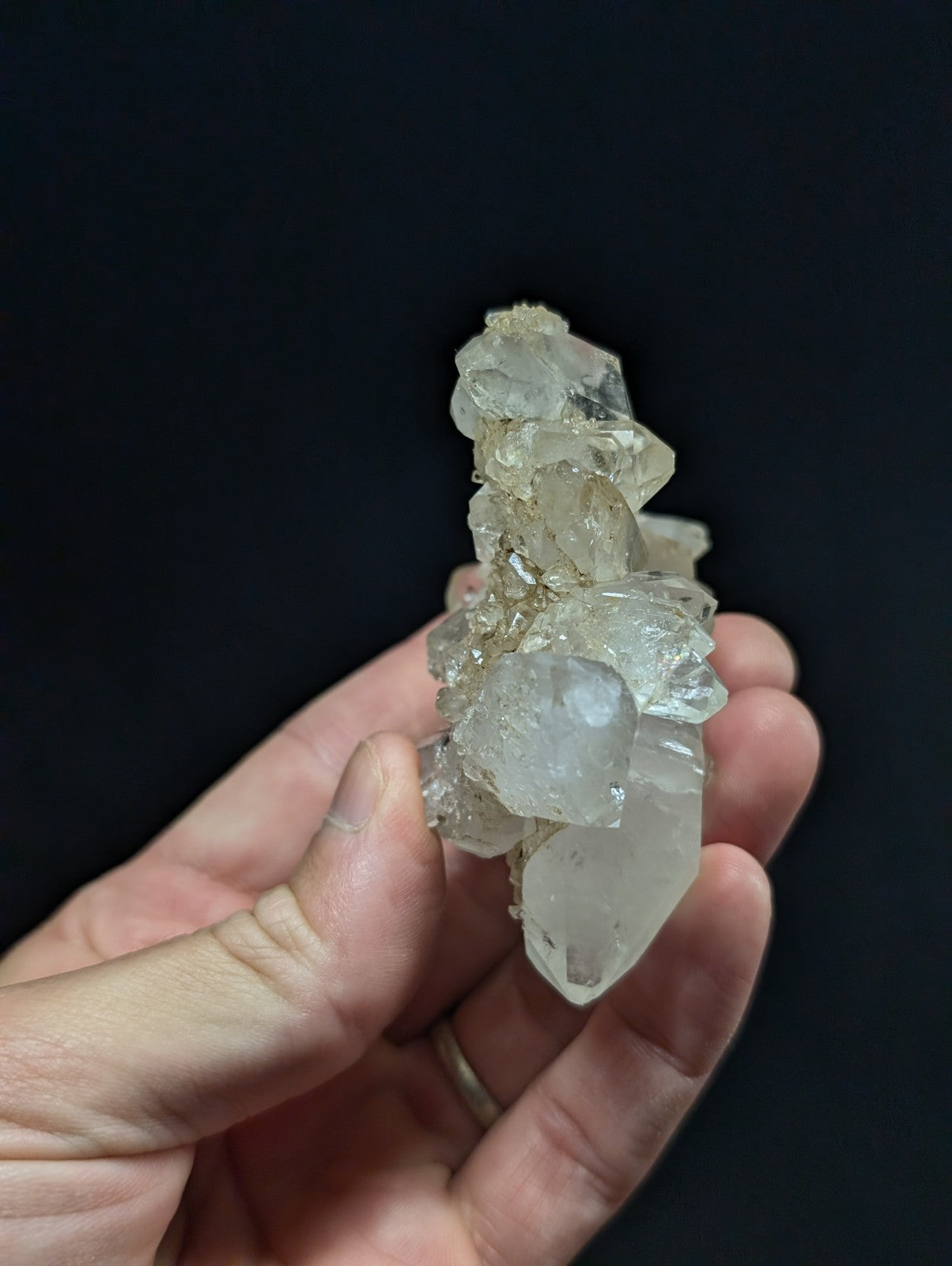 A translucent, clear quartz crystal cluster with jagged edges and a natural, earthy base.