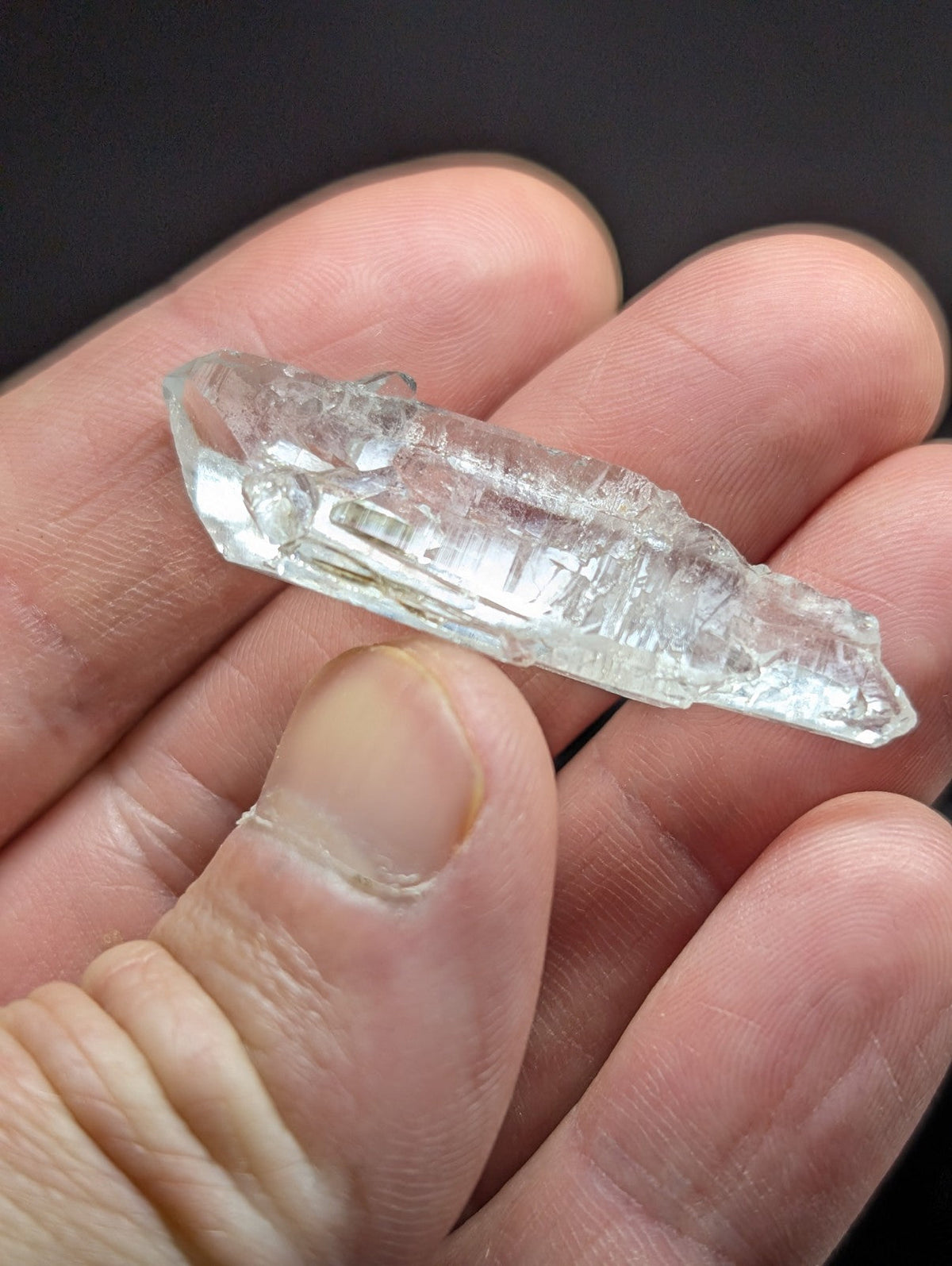A clear, translucent quartz crystal with visible internal striations and a pointed tip.