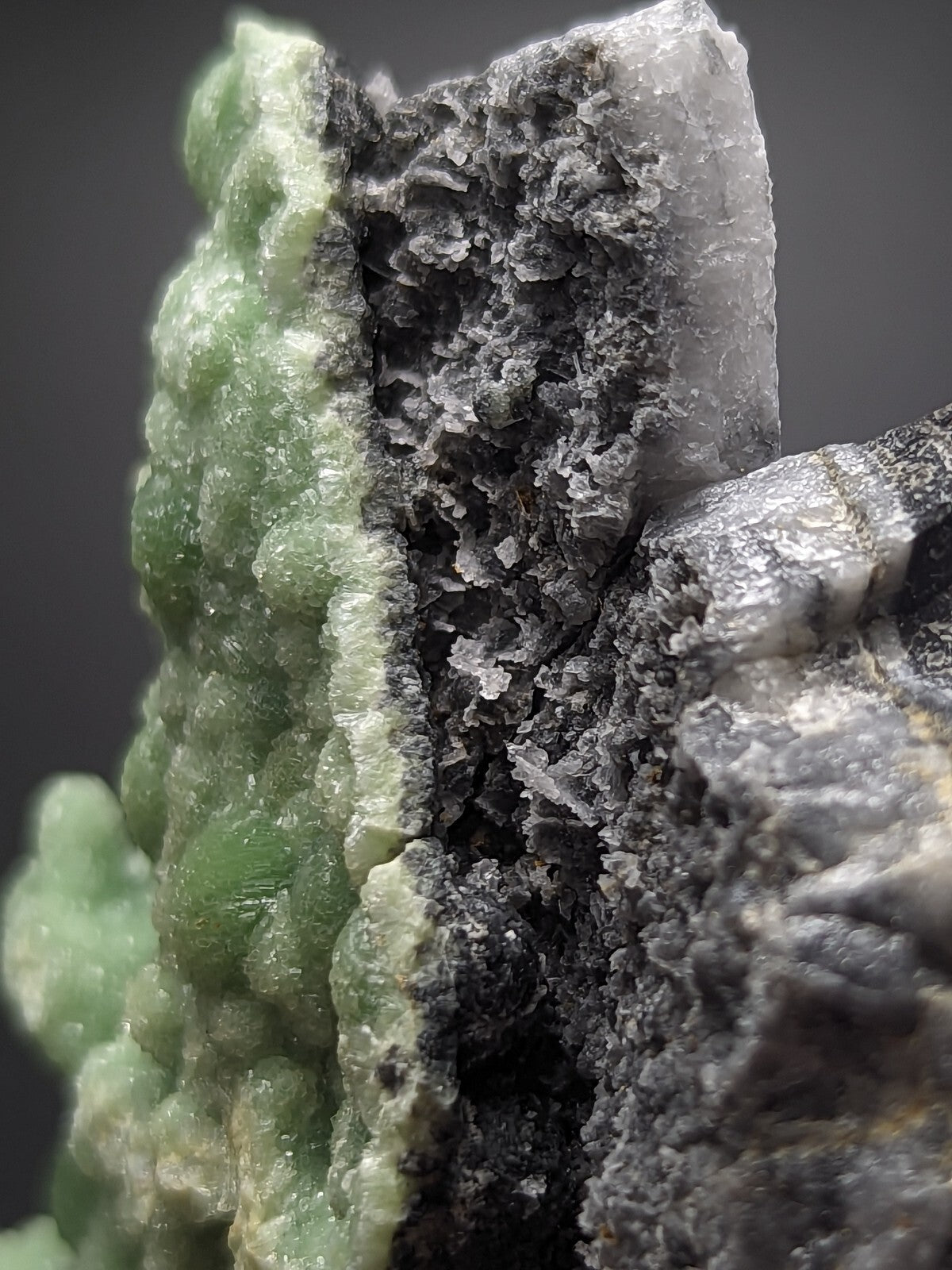 A striking green and gray mineral specimen featuring a textured, crystalline surface with translucent patches.
