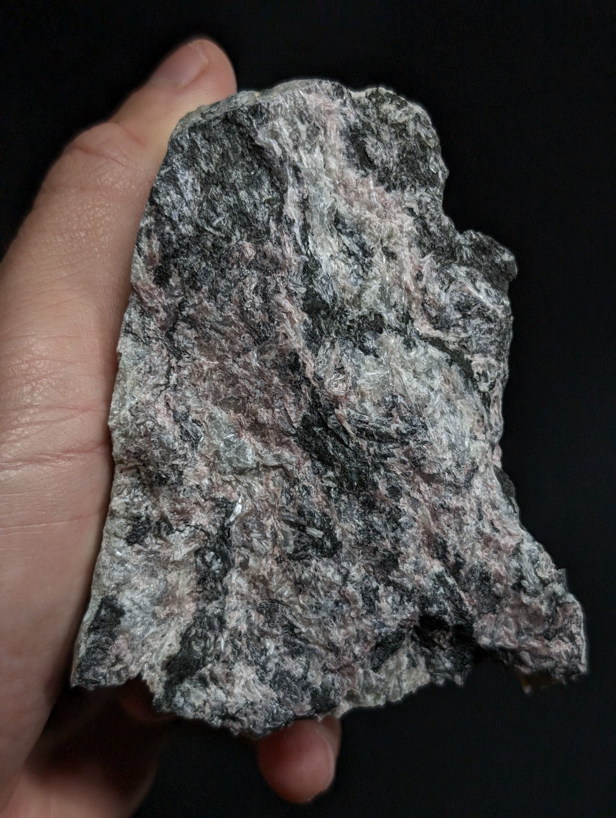 A rough, irregularly shaped stone with a mottled pattern of dark gray and light silver-gray hues.