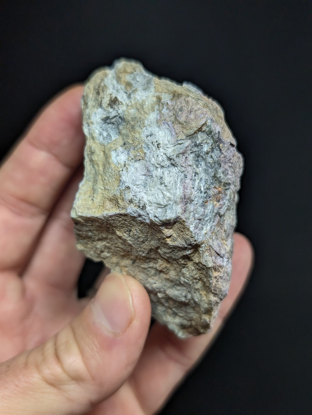 A rough, irregularly shaped rock with a mottled surface of gray and light green hues.