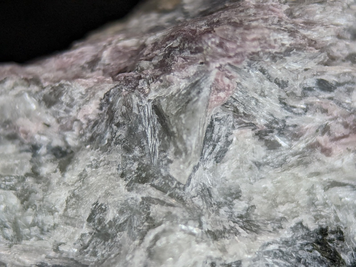 A rugged, naturally occurring rock specimen with a mottled surface of gray and pinkish hues.