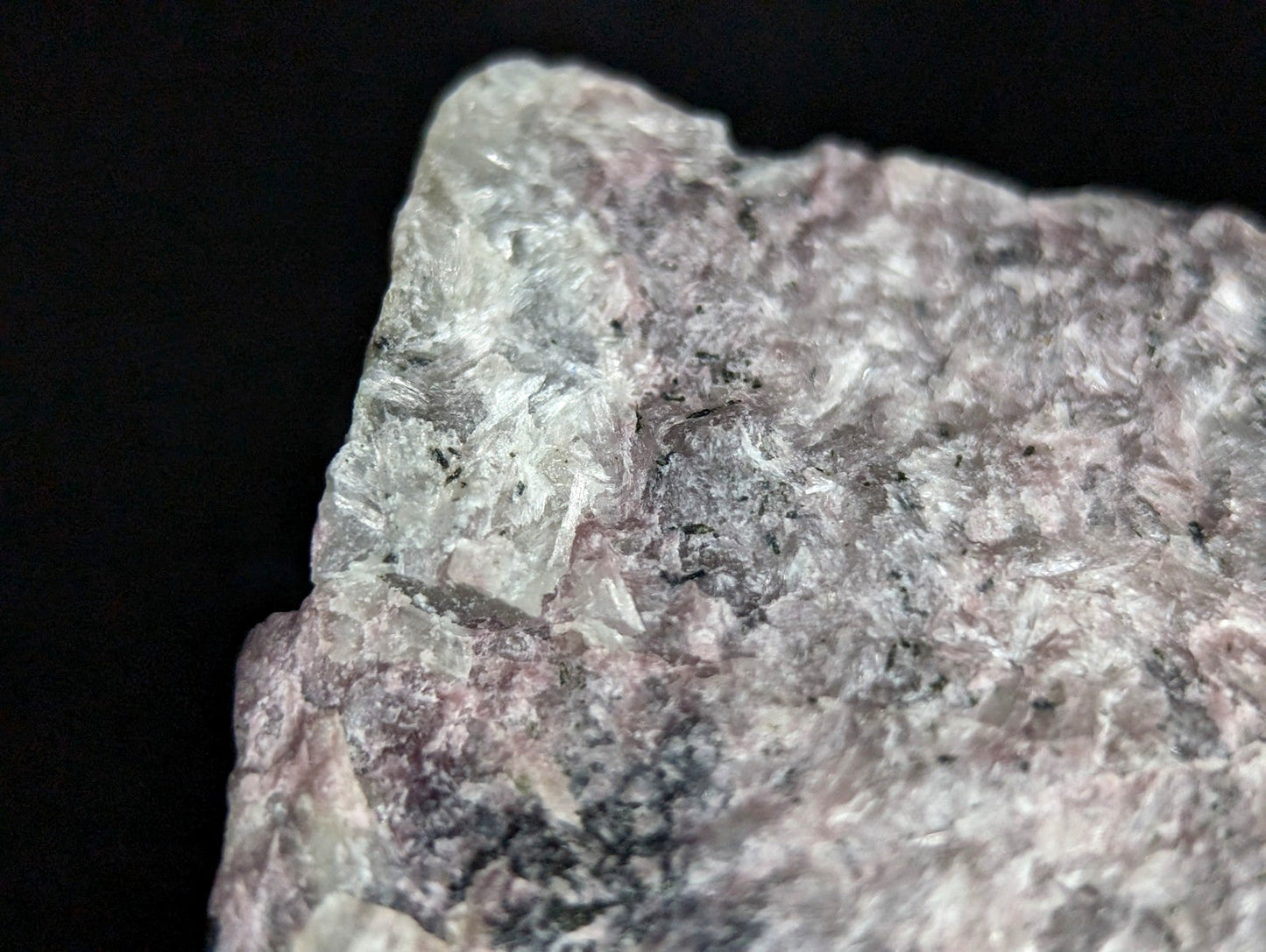 A rough, irregularly shaped piece of pinkish-gray mineral rock with a textured surface and visible crystalline formations.