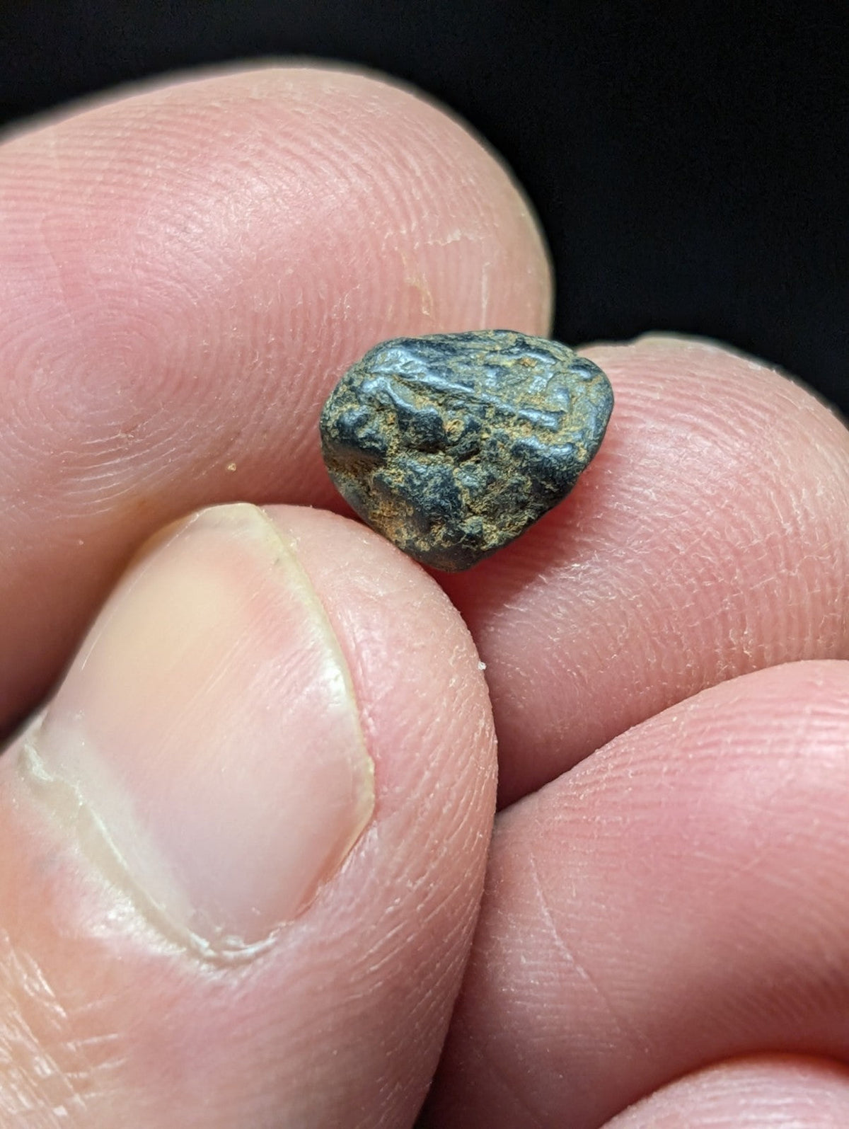 A small, irregularly shaped ancient bronze coin with a greenish patina and faint engraved markings.