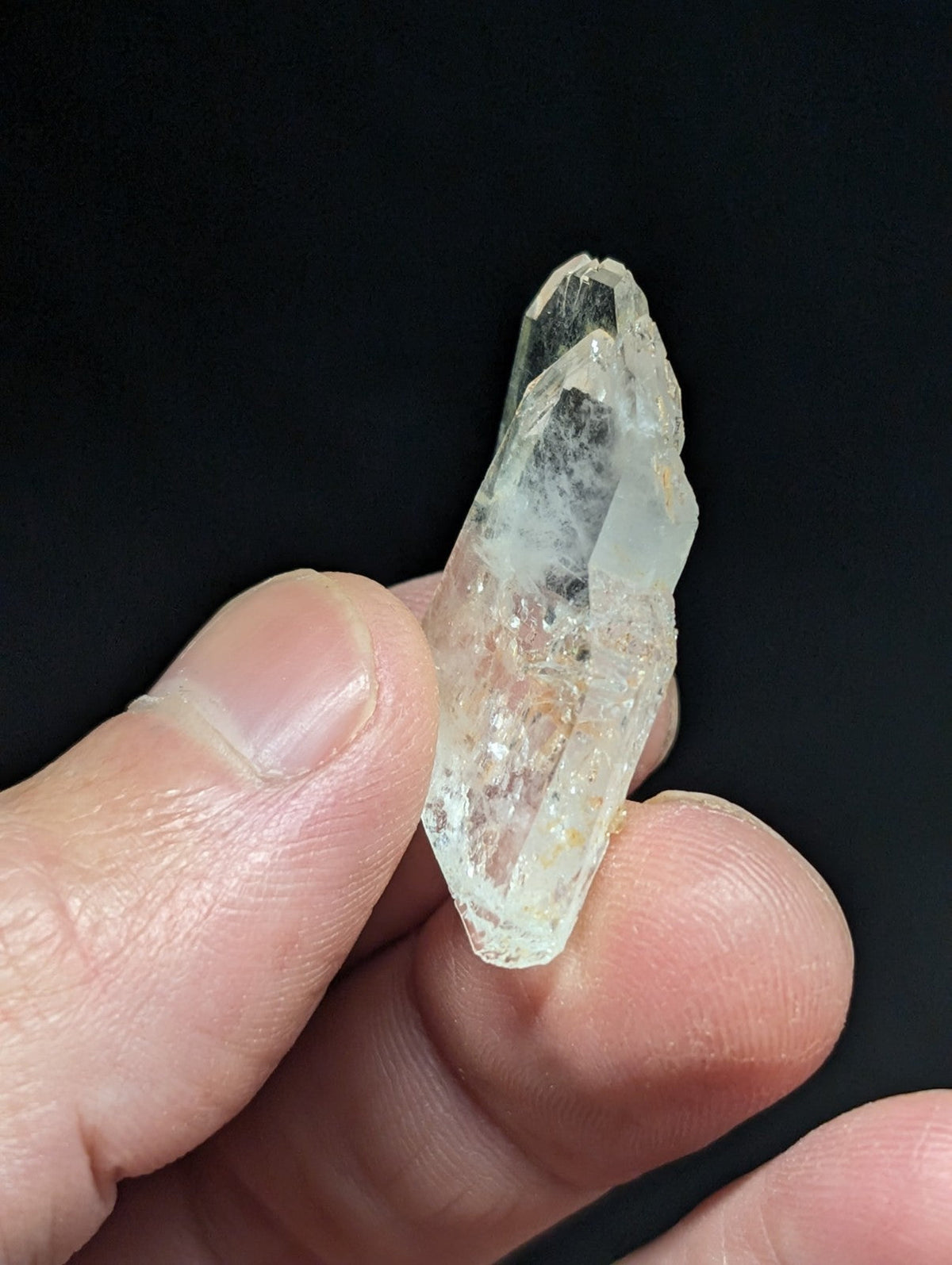 A translucent, clear quartz crystal with a pointed tip and natural facets.