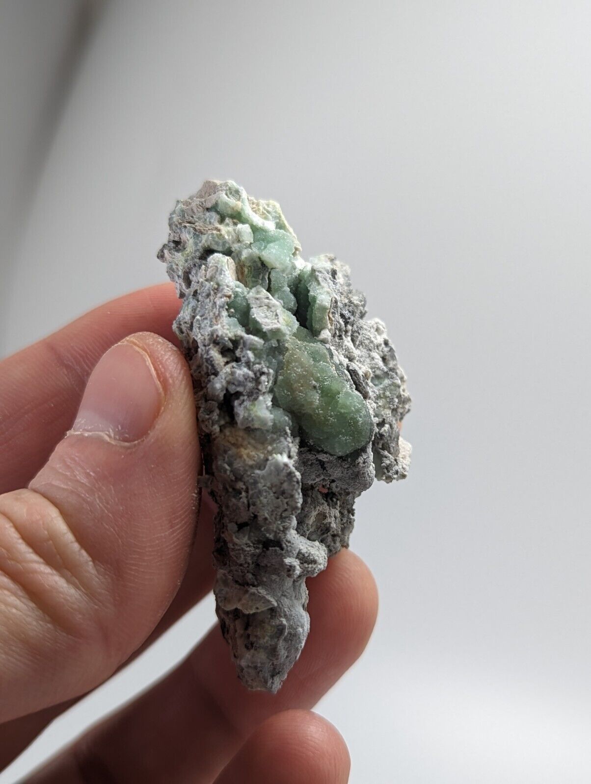 Green mineral specimen on gray matrix.