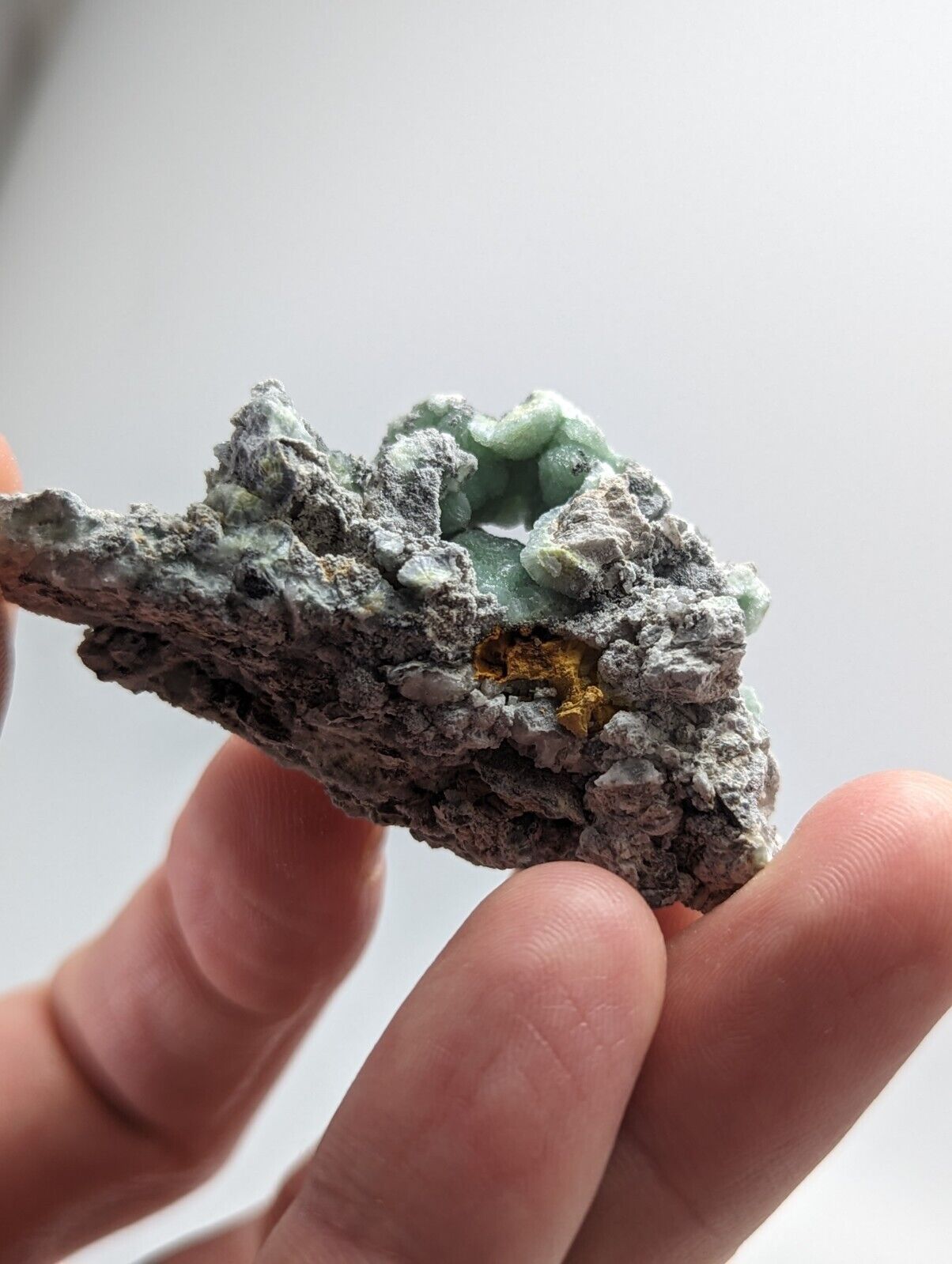 Rough mineral specimen with green and gold inclusions.