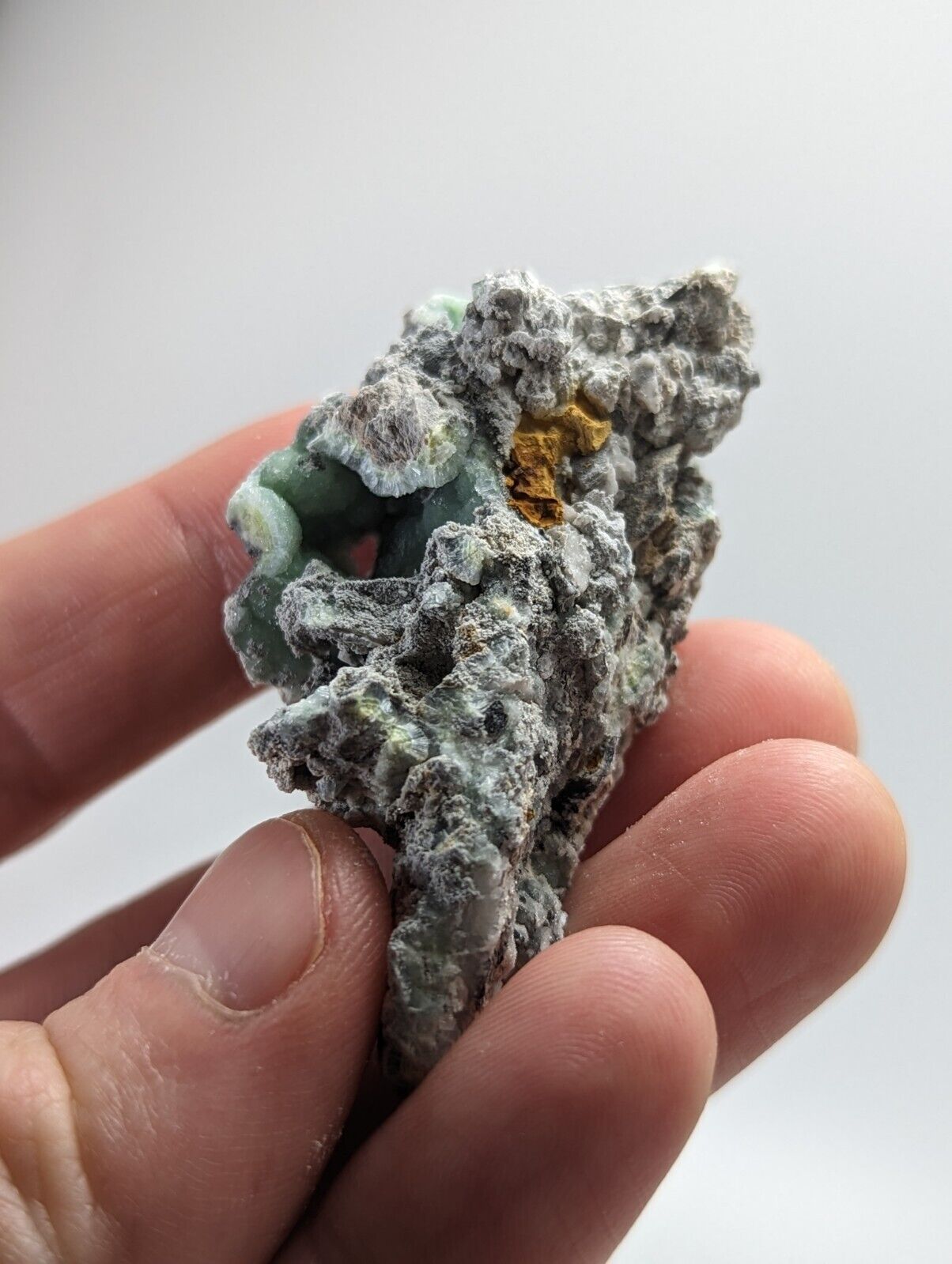 Rough, textured mineral specimen with green and yellow accents.
