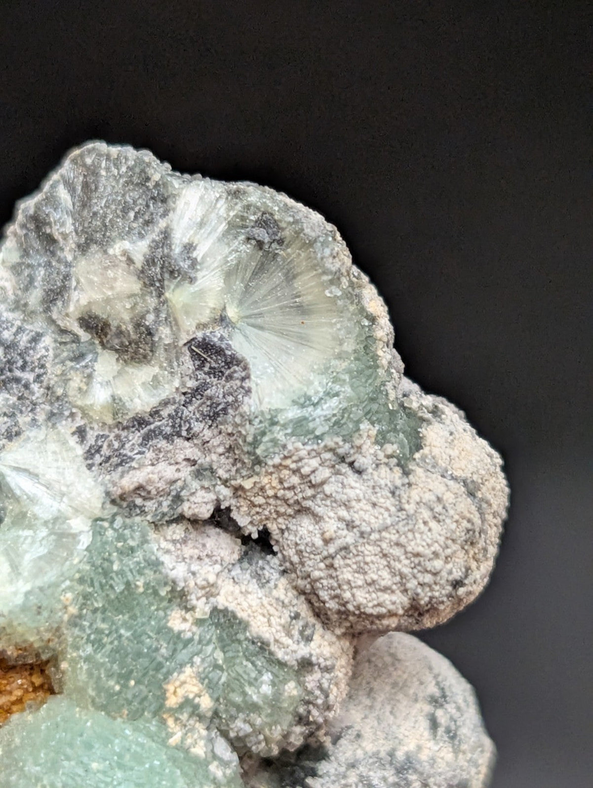 A translucent green fluorite specimen with a crystalline, fan-like formation and patches of grayish matrix.