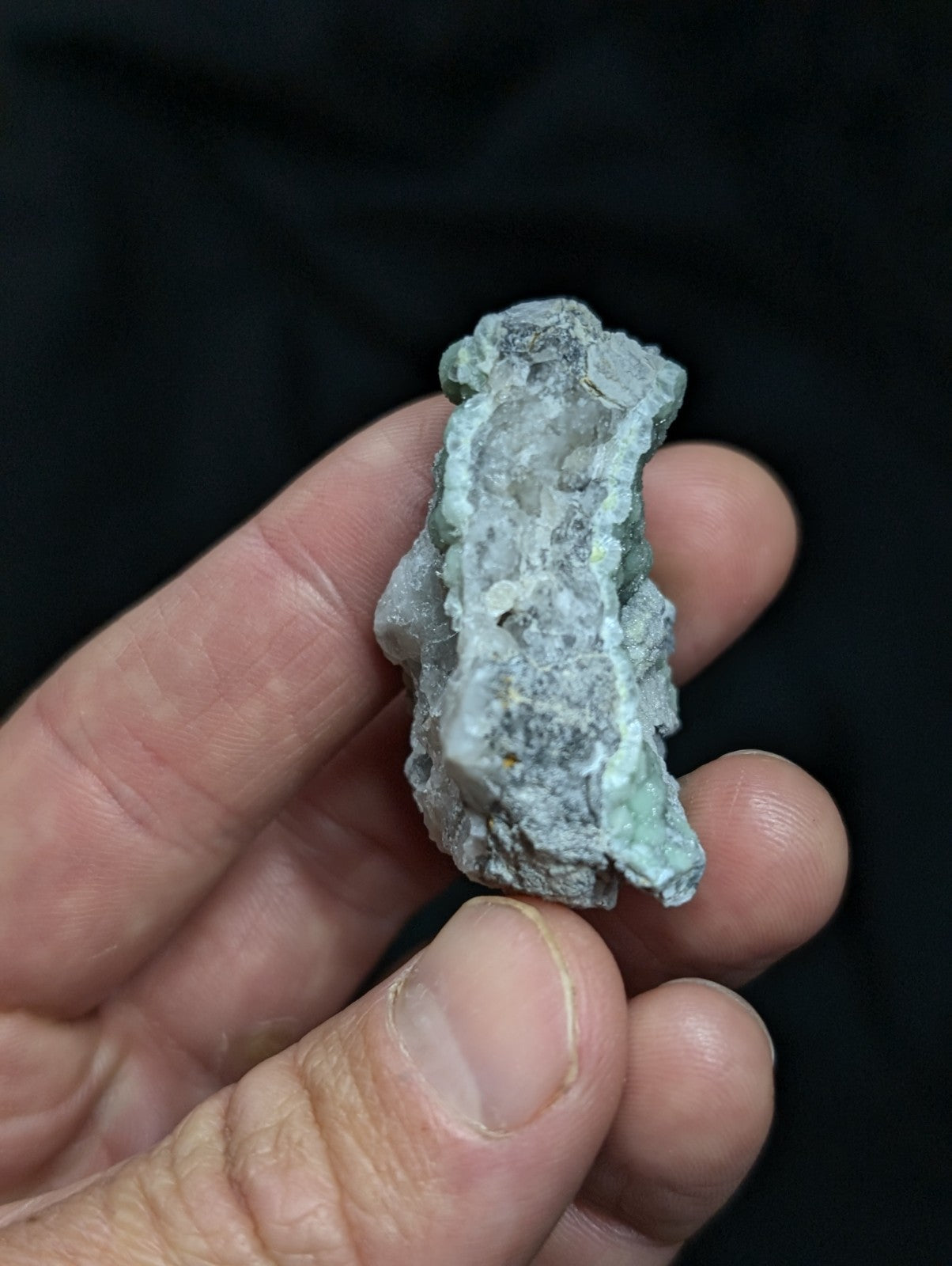 A rough, irregularly shaped mineral specimen with a mottled greenish-blue and gray surface.
