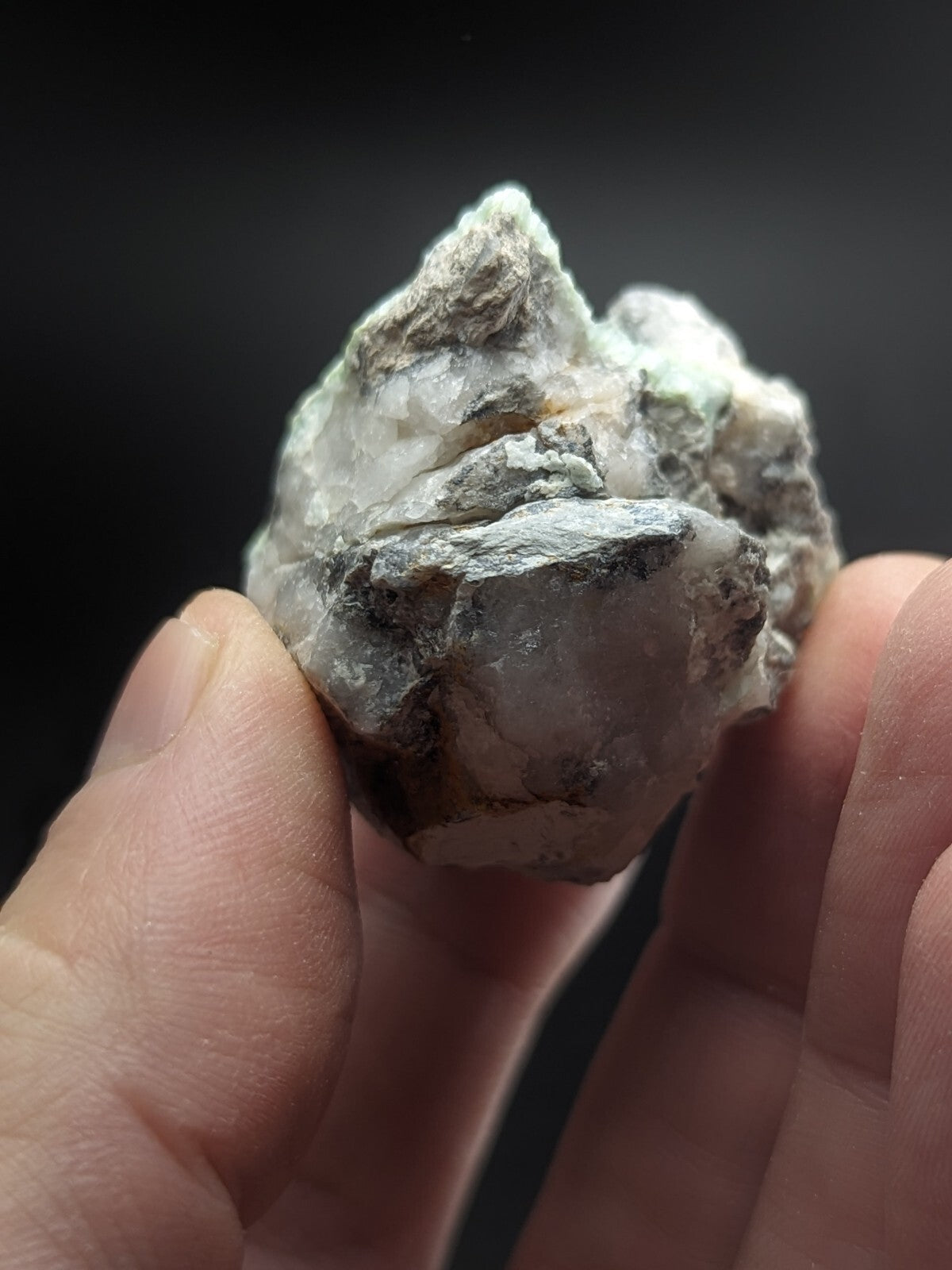 A rough, irregularly shaped mineral specimen with translucent white and gray crystalline sections accented by darker patches of matrix material.
