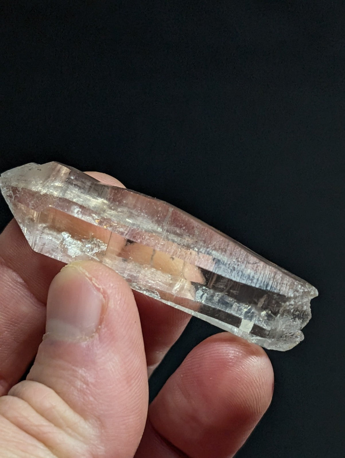 A translucent, clear quartz crystal with natural internal inclusions and a pointed tip.