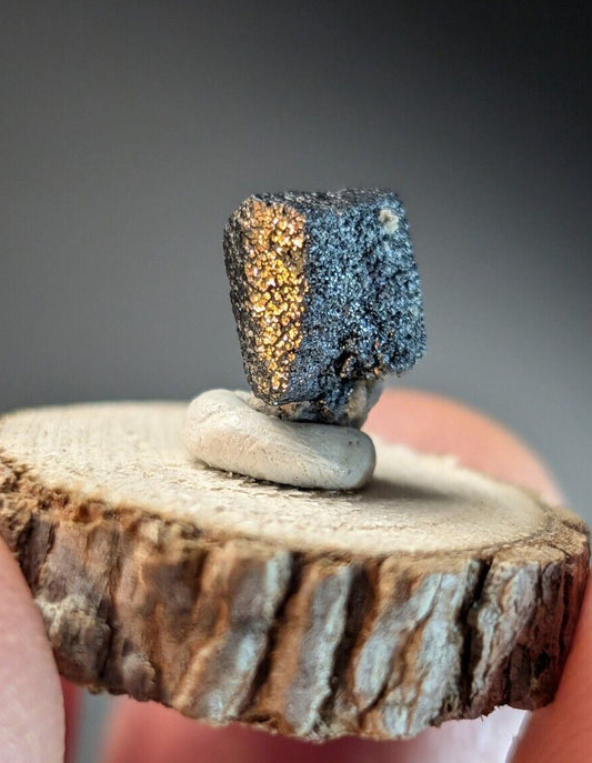 Metallic cube with gold and dark gray facets.