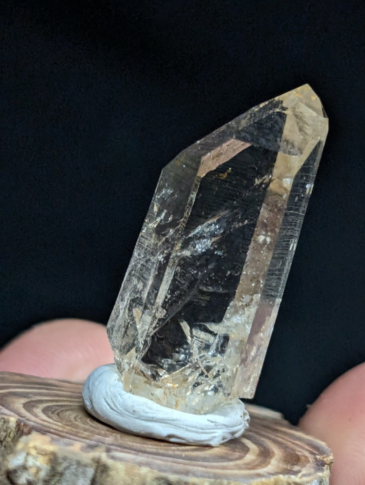 A translucent, pale yellowish quartz crystal with natural inclusions and facets stands upright on a light gray circular base.