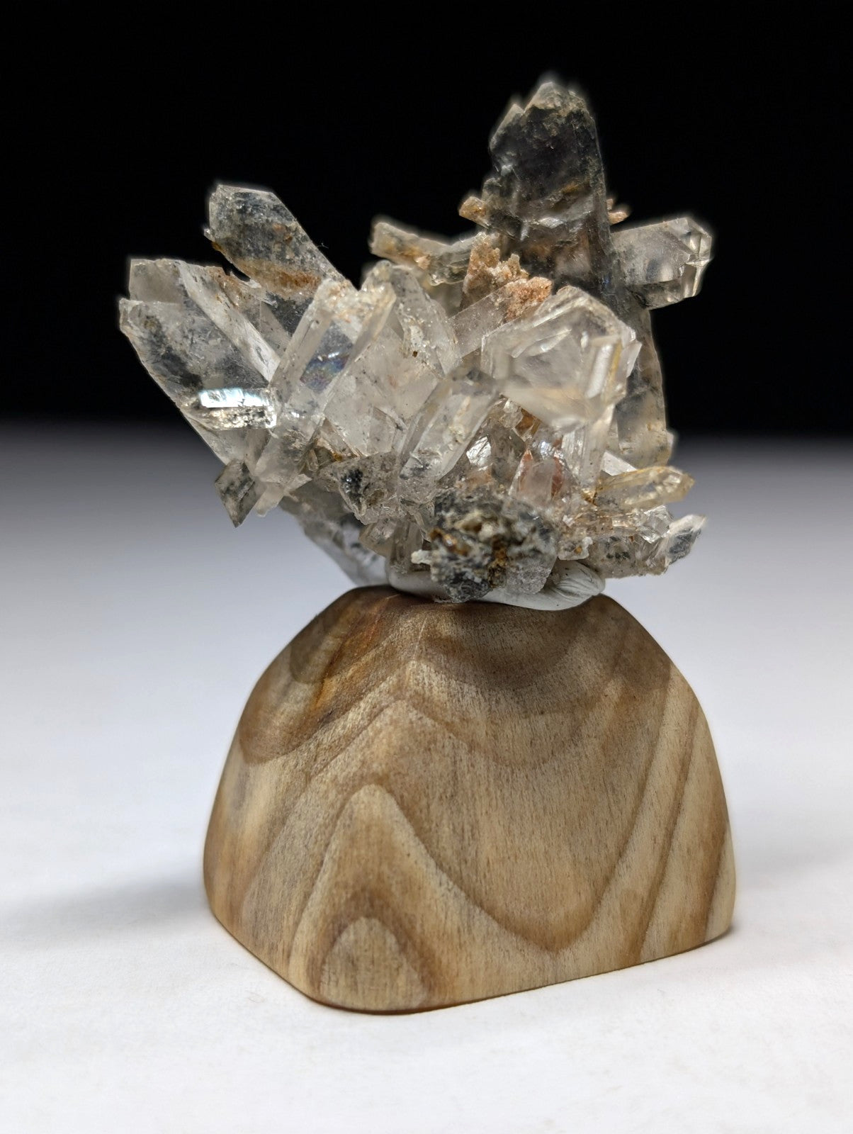Clear quartz crystal cluster mounted on a wooden base.