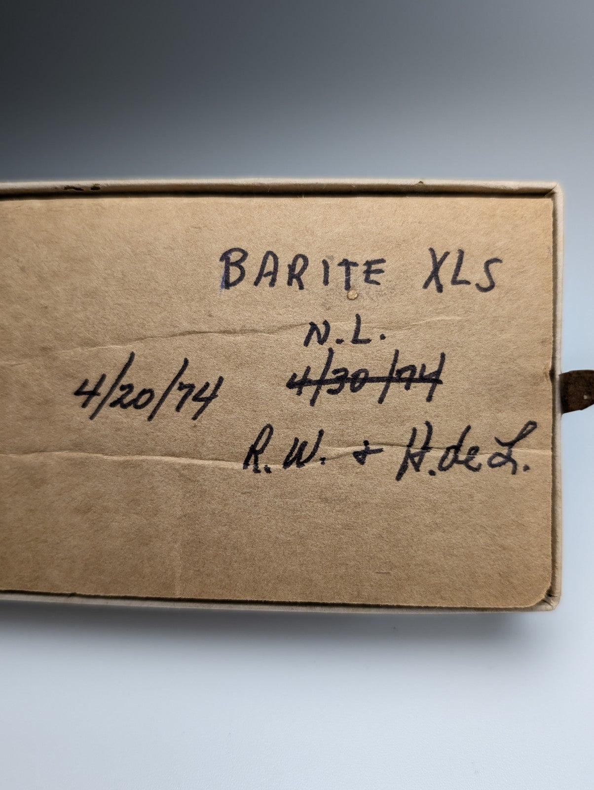 A brown cardboard box with handwritten barite xls markings containing a plus barite crystal from magnet cove arkansas