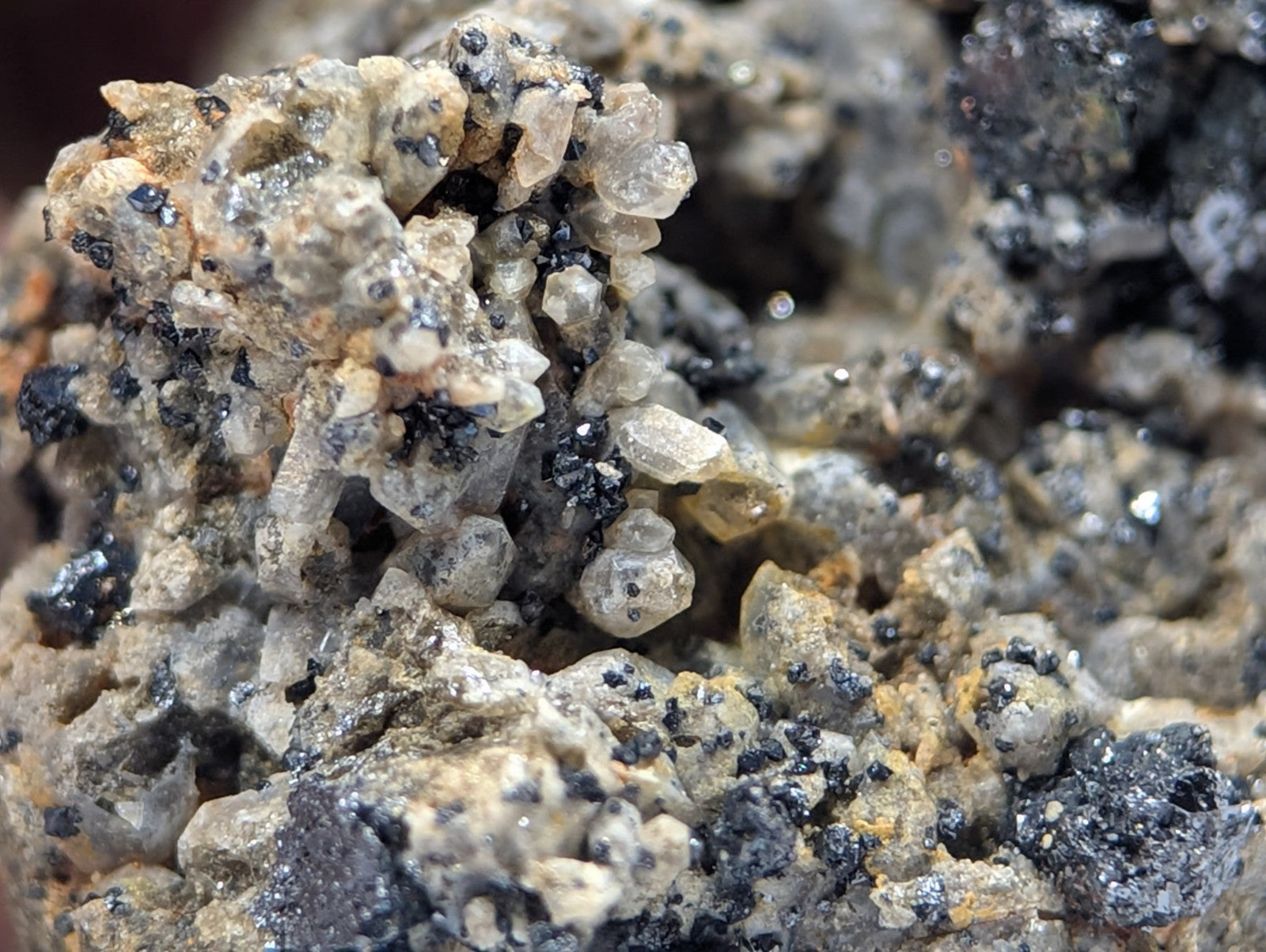 A cluster of translucent, crystalline minerals with specks of black and yellowish-brown matrix.